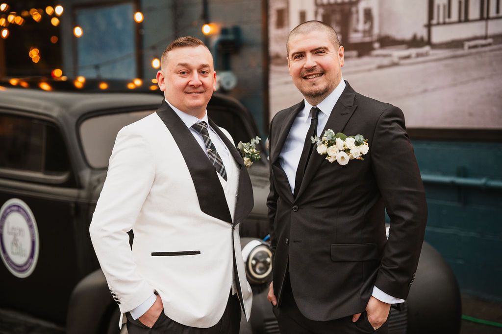 Groomsmen in black suits and white jackets pose for formal wedding photos.