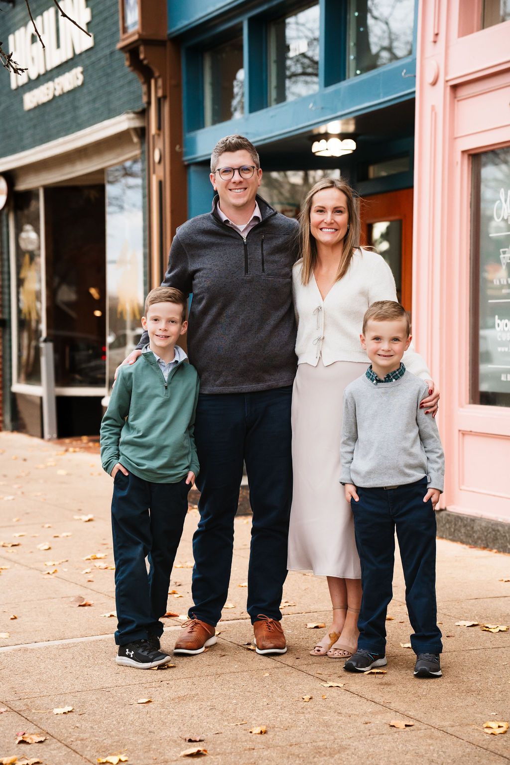 Urban family photography session along a charming storefront with brick buildings.