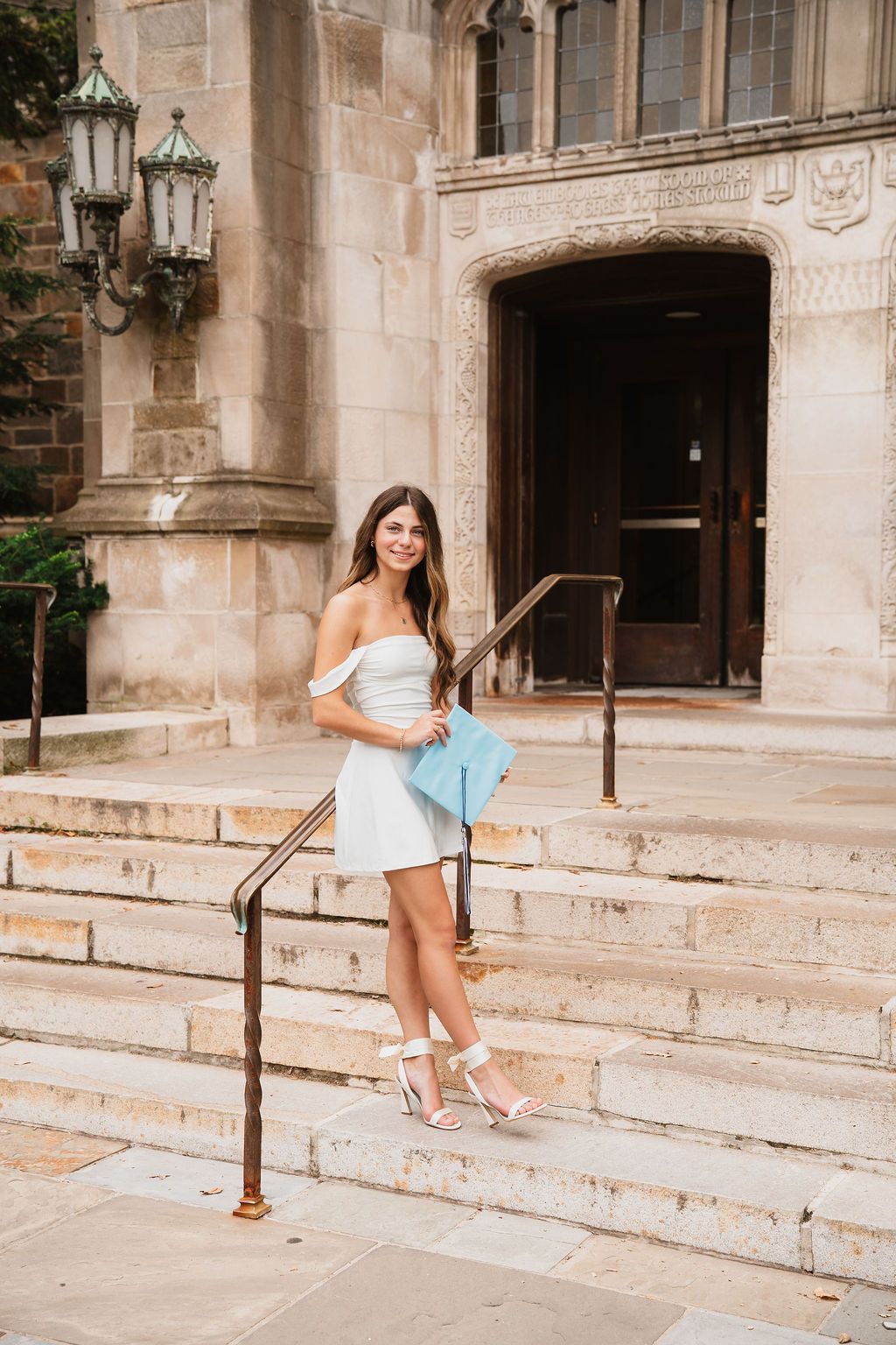 A woman in a white dress poses on stone steps outside a historic building entrance in a photo series.