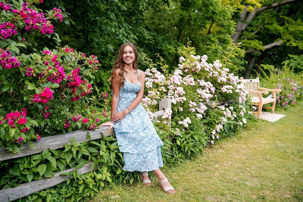 Portrait session in floral garden with pink and white blooming flowers in background.