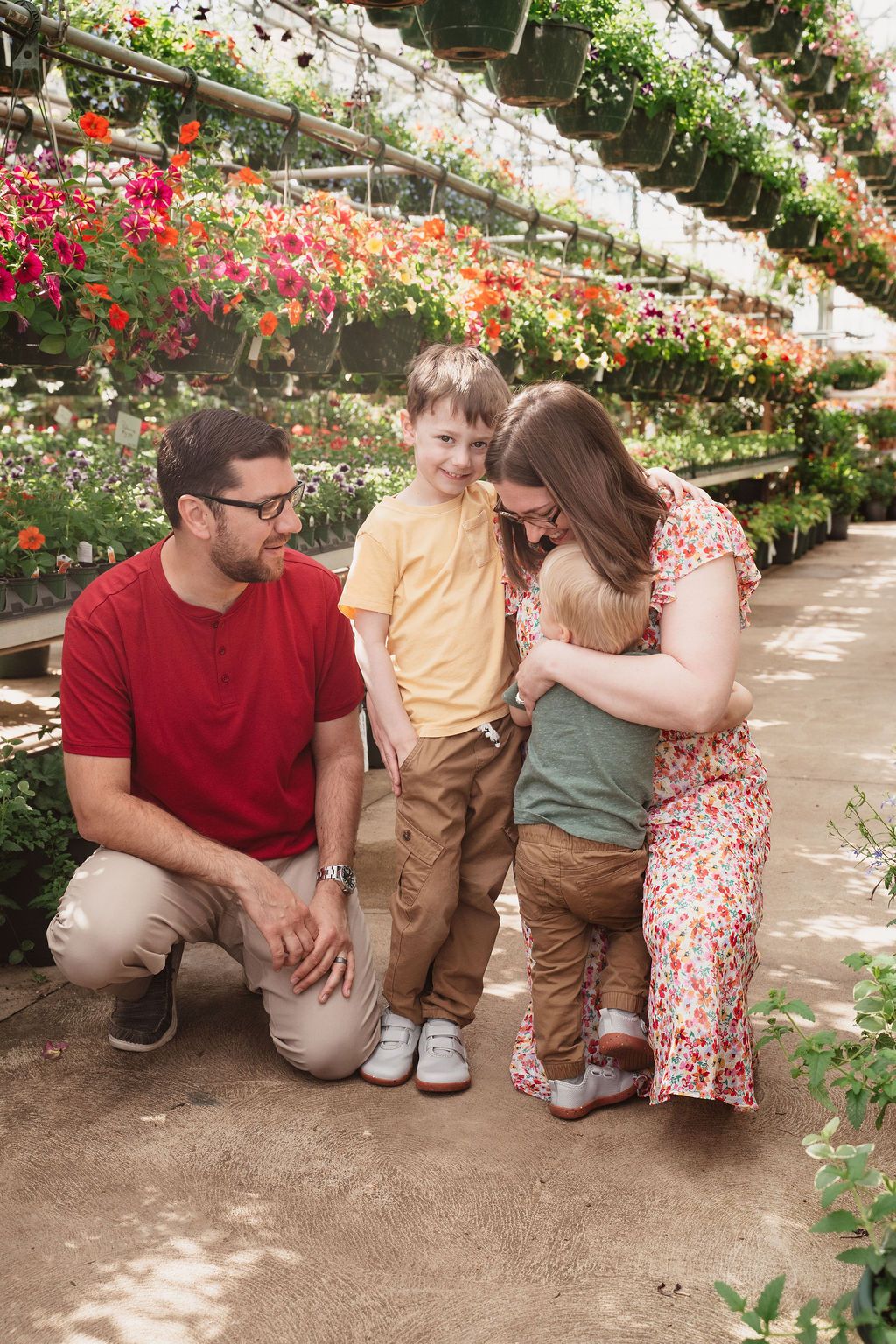 Family of four enjoying a stroll through a colorful greenhouse filled with blooming flowers.