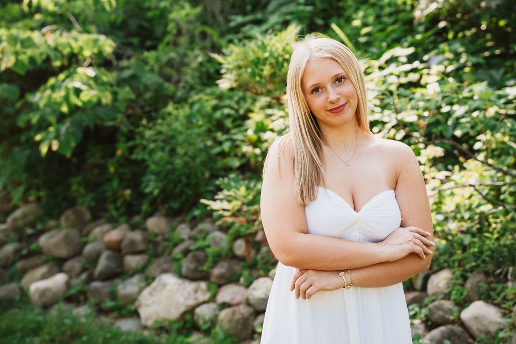 Elegant white dress portrait session in a landscaped garden setting.