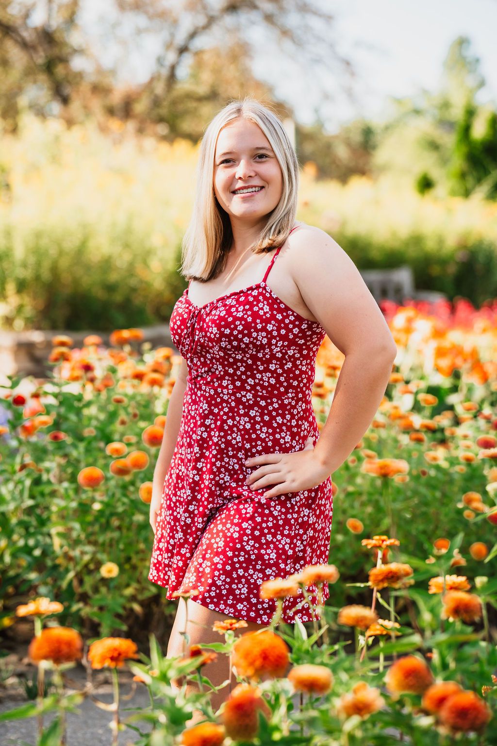A red polka dot dress stands out against a vibrant orange flower garden on a sunny day.