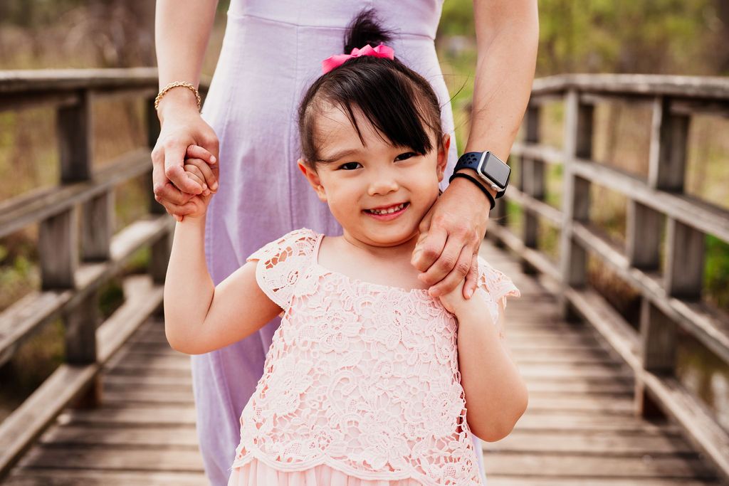 A series of connected photos showing joyful moments between parent and child on a wooden bridge outdoors.