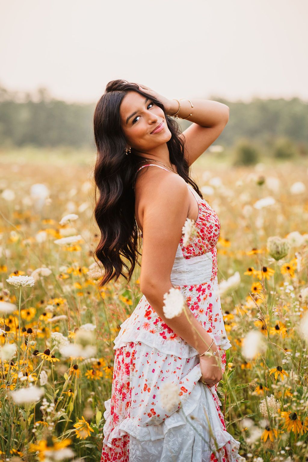 Portrait session in a summer meadow with yellow and white wildflowers at sunset.