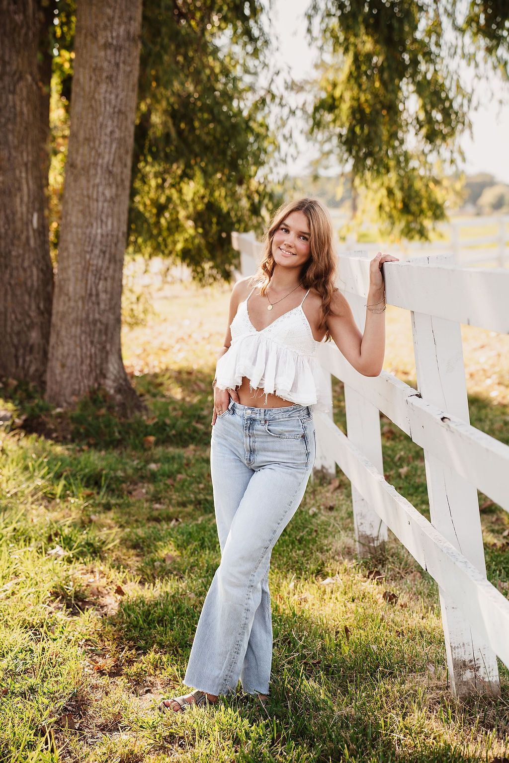 Rustic outdoor photography session by a white fence in warm evening light.