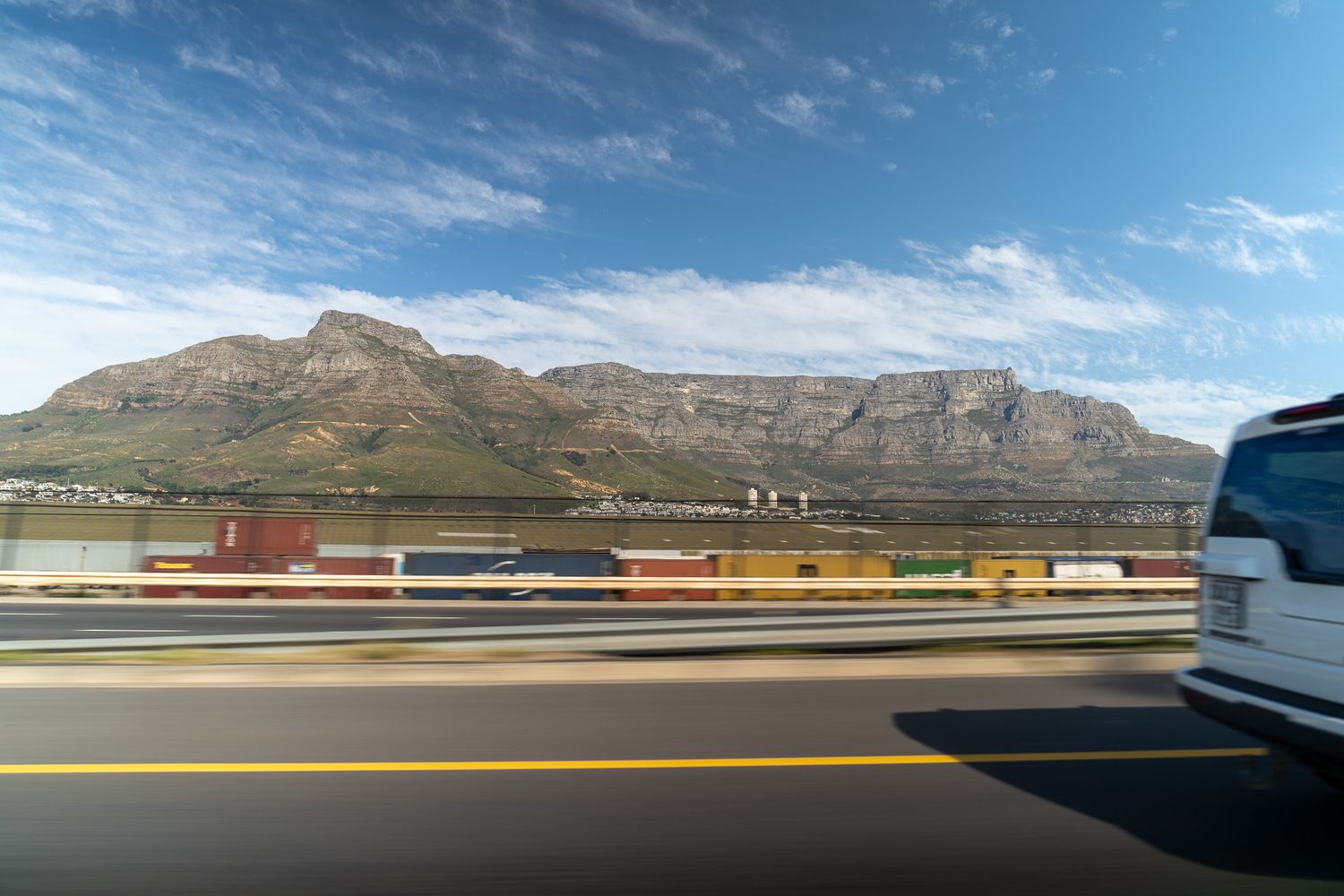 Panoramic view of mountain ranges under blue skies with scattered clouds.