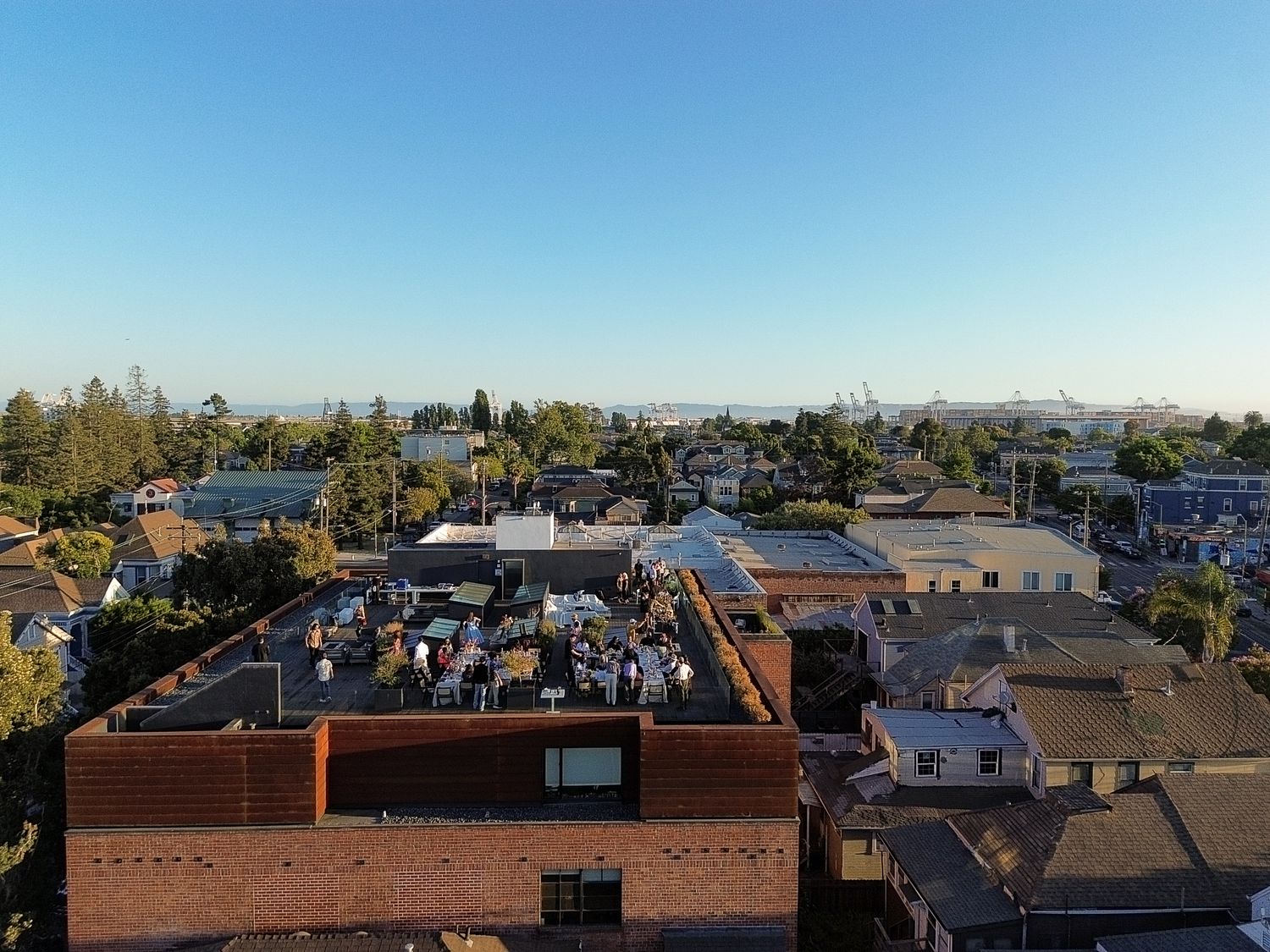 Panoramic view of residential rooftops and buildings against a clear blue sky.