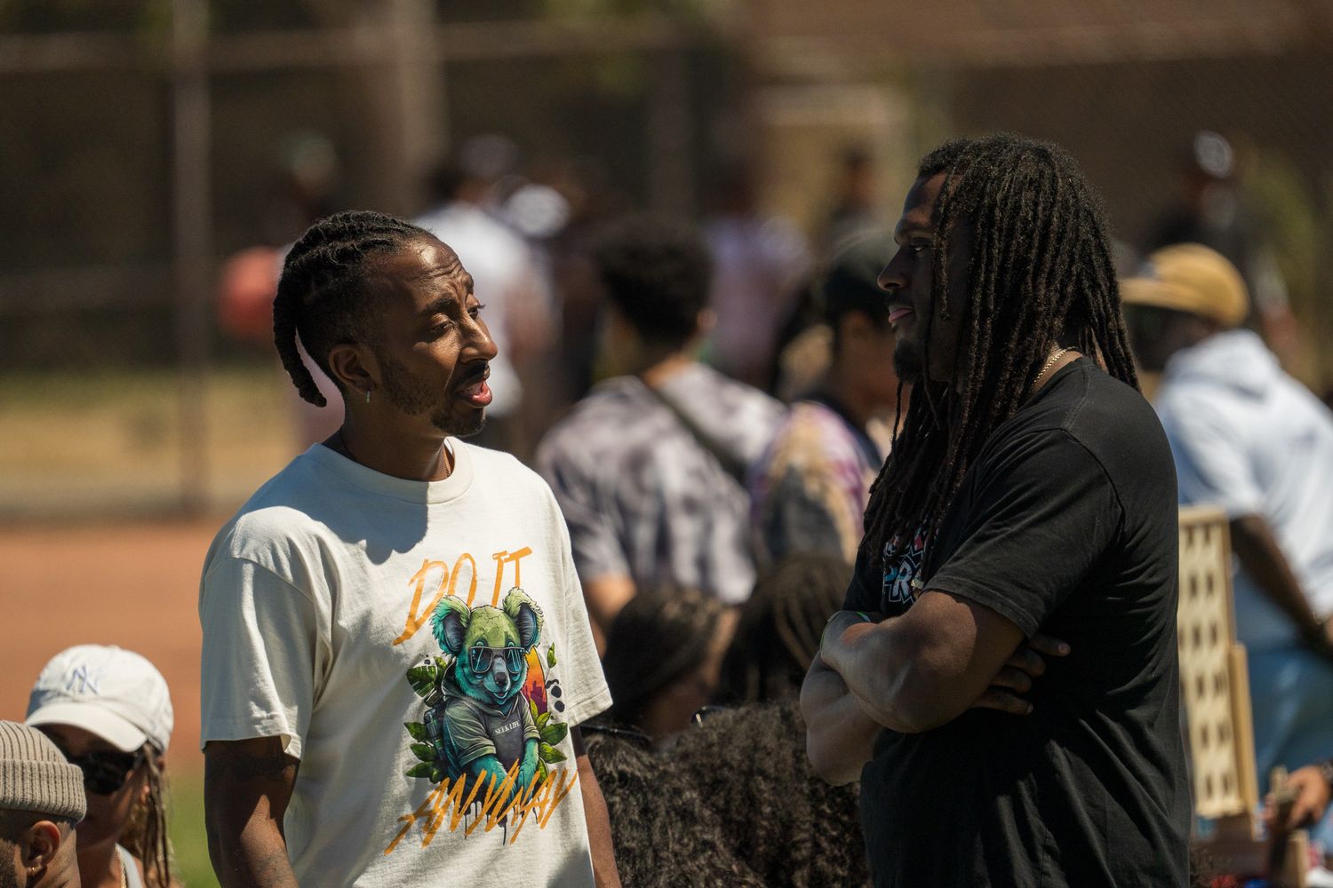 Crowd of people gathered outdoors at a community event on a sunny day.