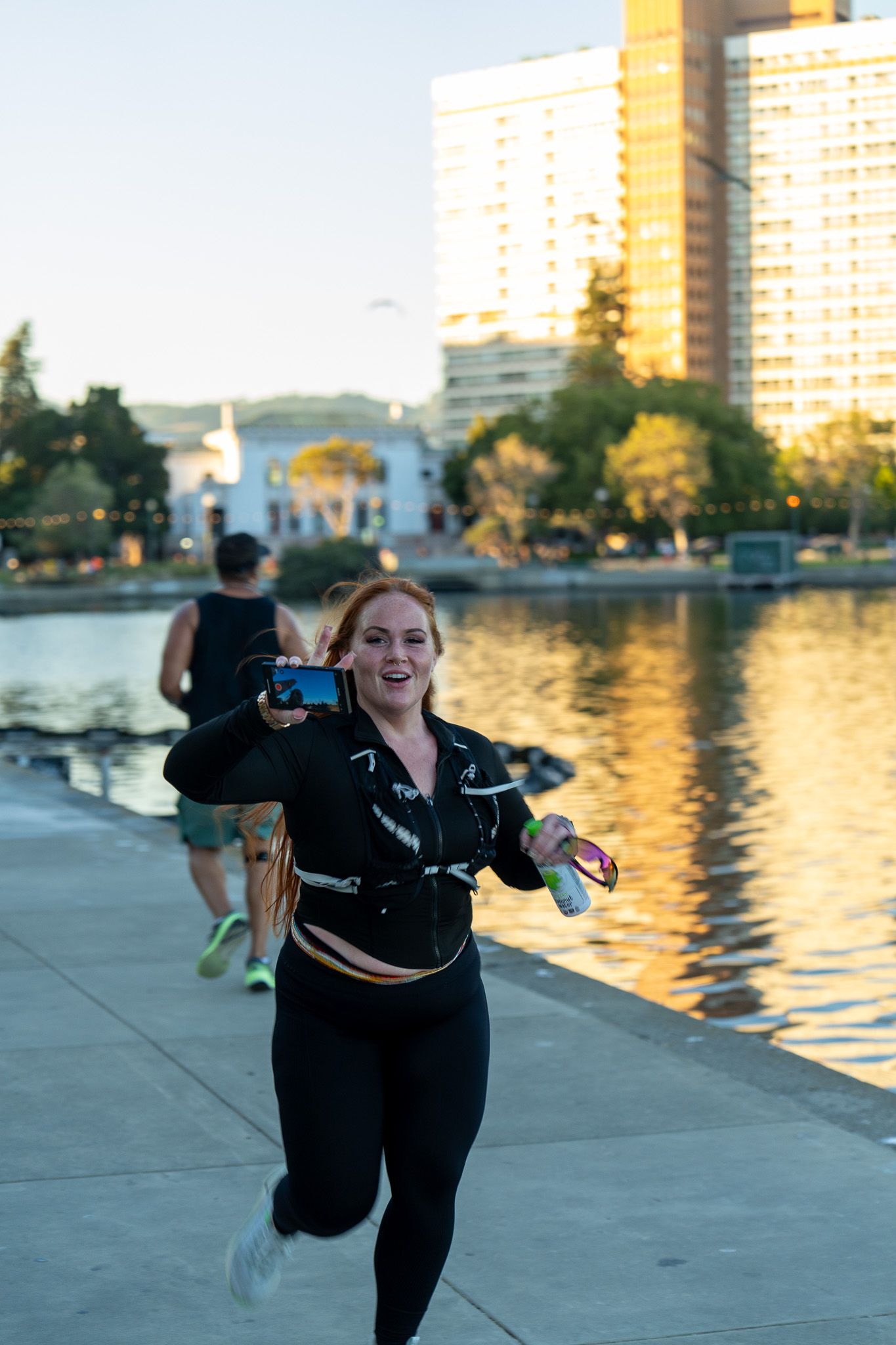 Athlete exercising along a waterfront with city buildings in the background during golden hour.