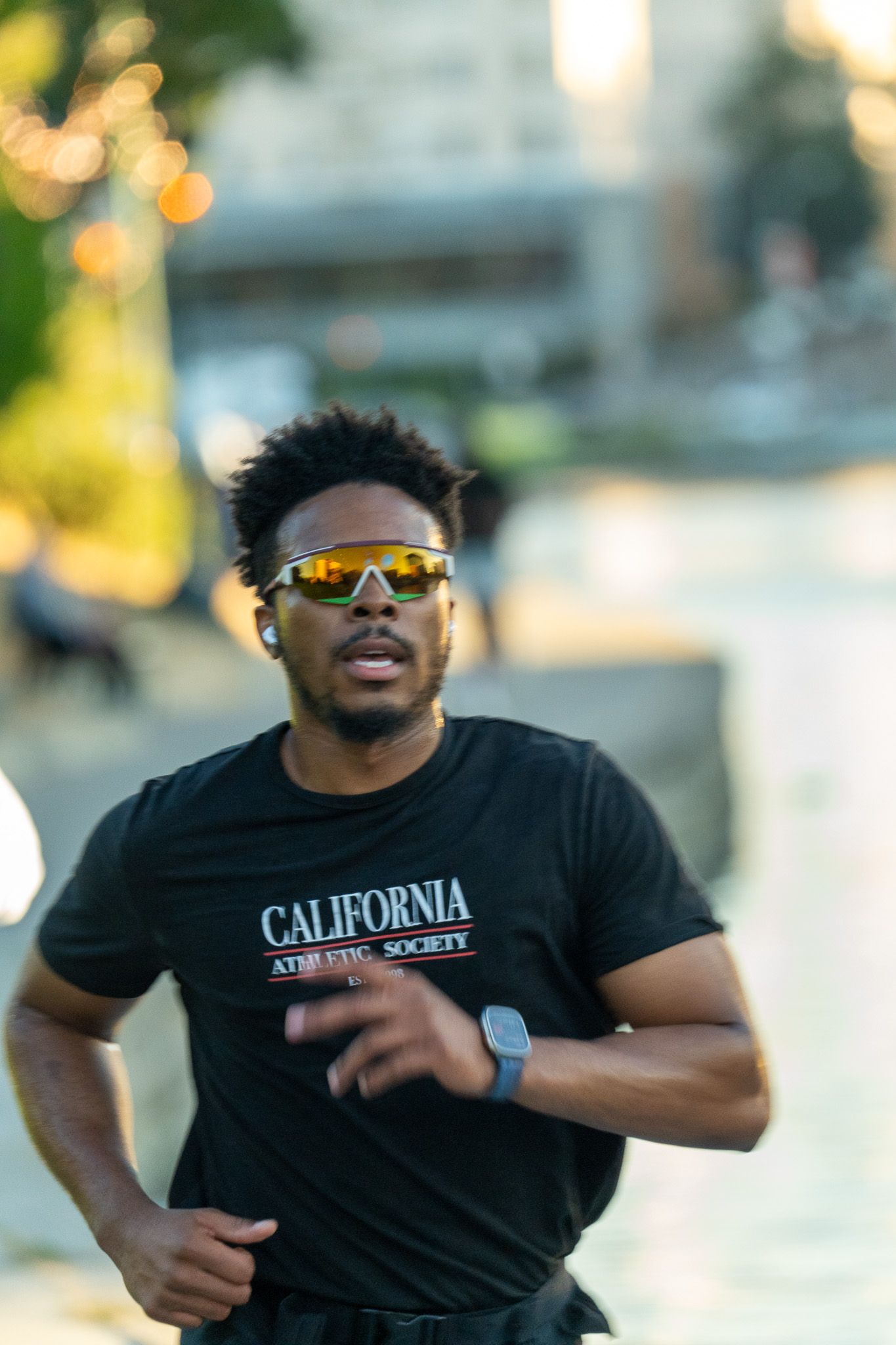 Joggers running on a path during golden hour wearing athletic gear.