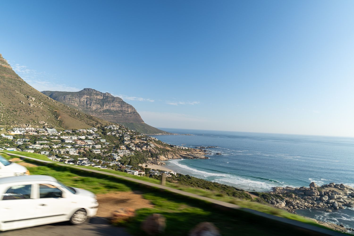 Coastal road curves along mountainous shoreline with ocean views.