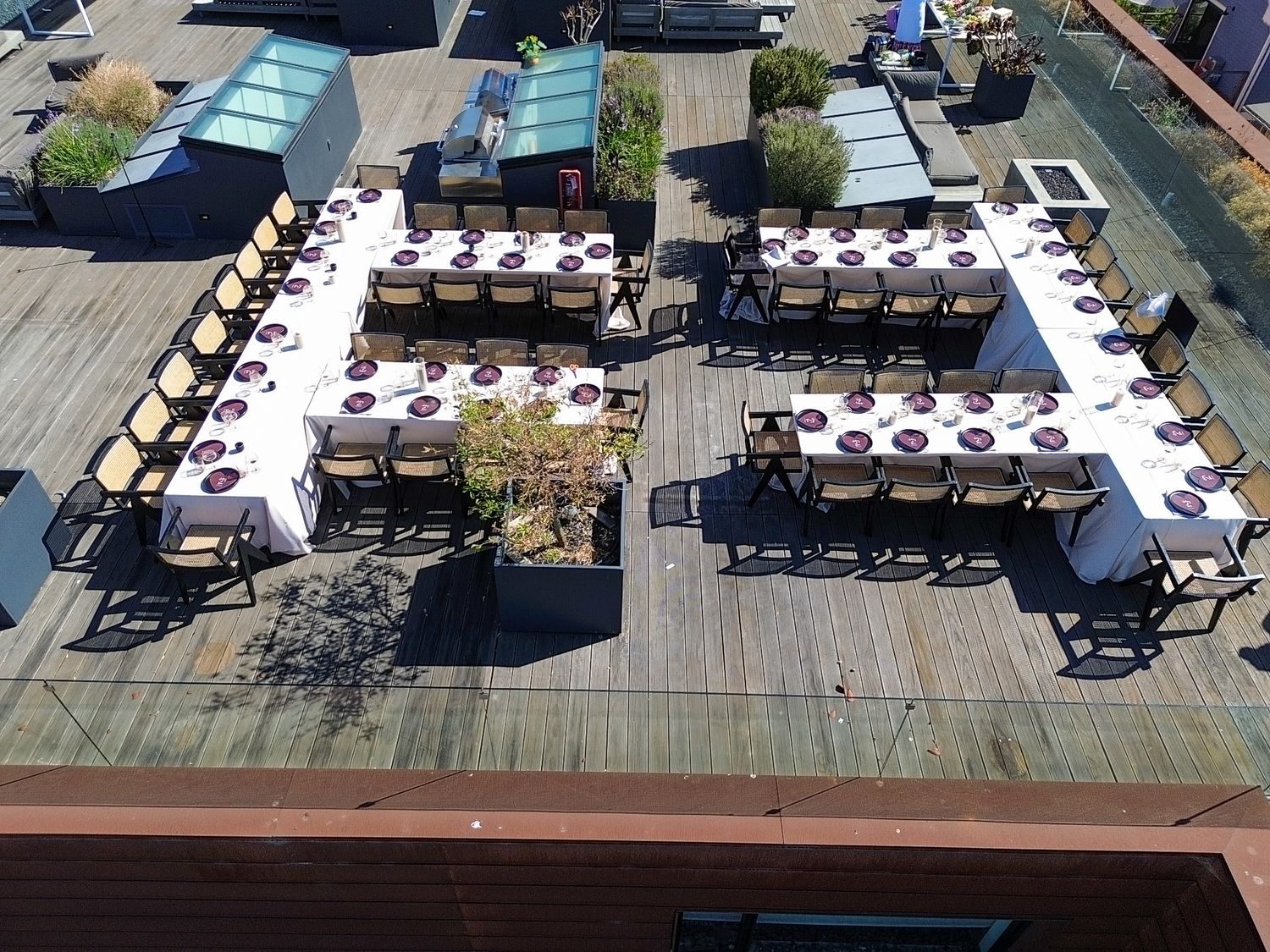 Overhead view of empty dining tables set up on a wooden deck terrace.