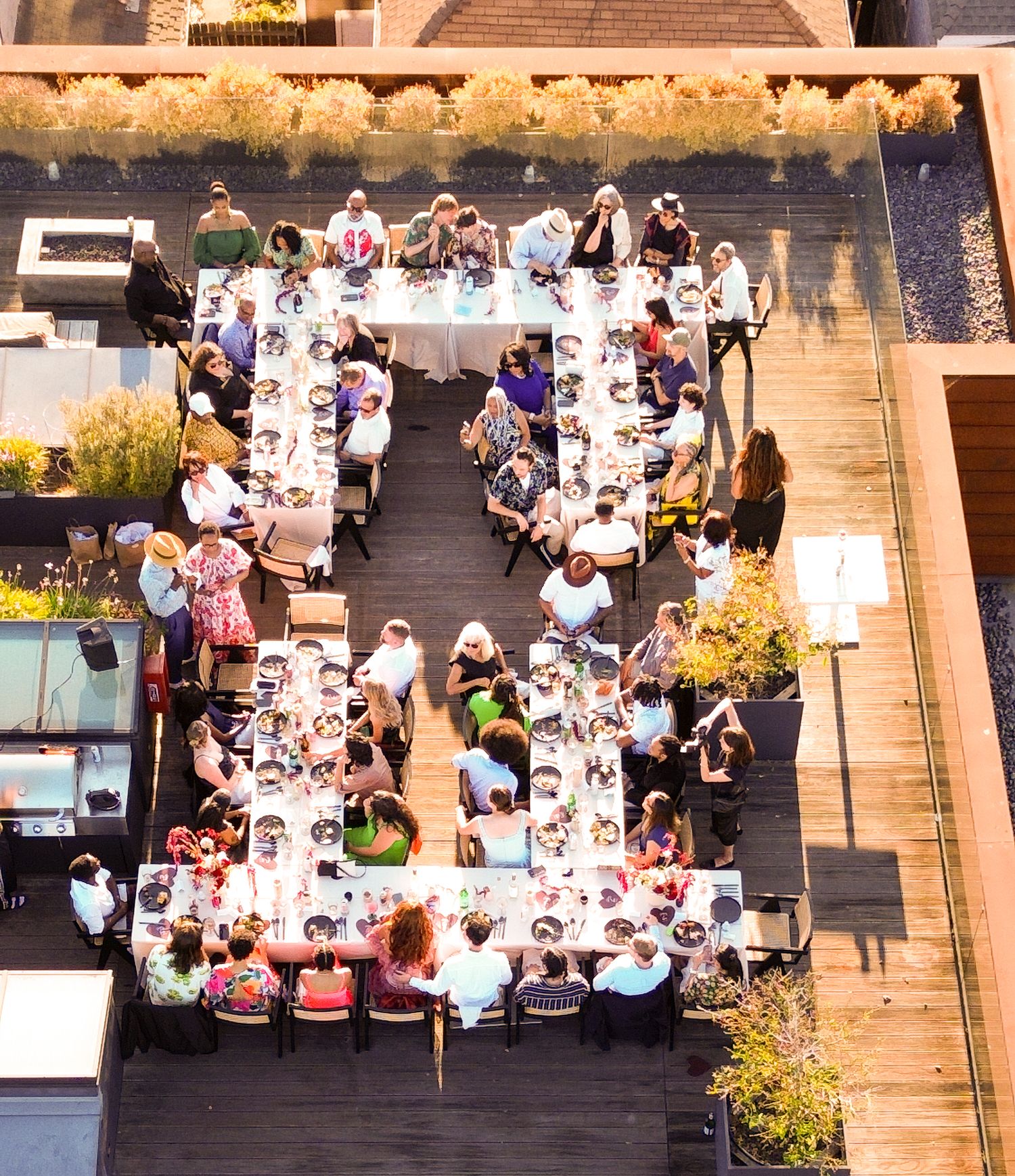 Diners enjoying an outdoor meal at long communal tables arranged on city steps during a special street event at dusk.