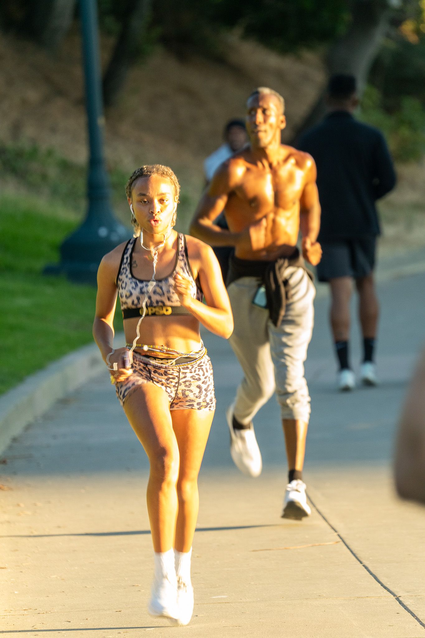 Athletes exercising on an outdoor path during a sunny evening workout.