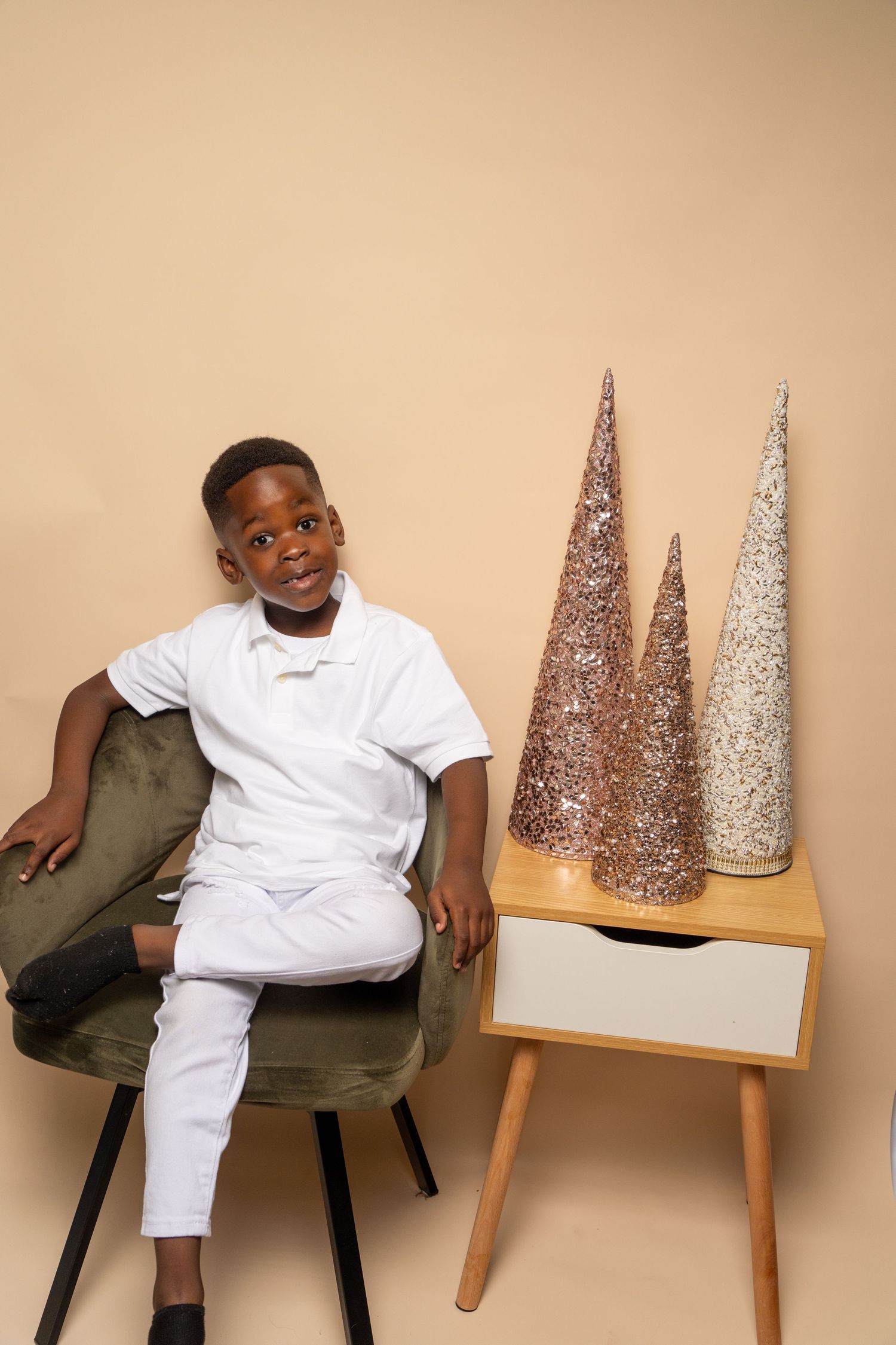 Modern studio setup with sparkly cone decorations and green velvet chair against beige walls.