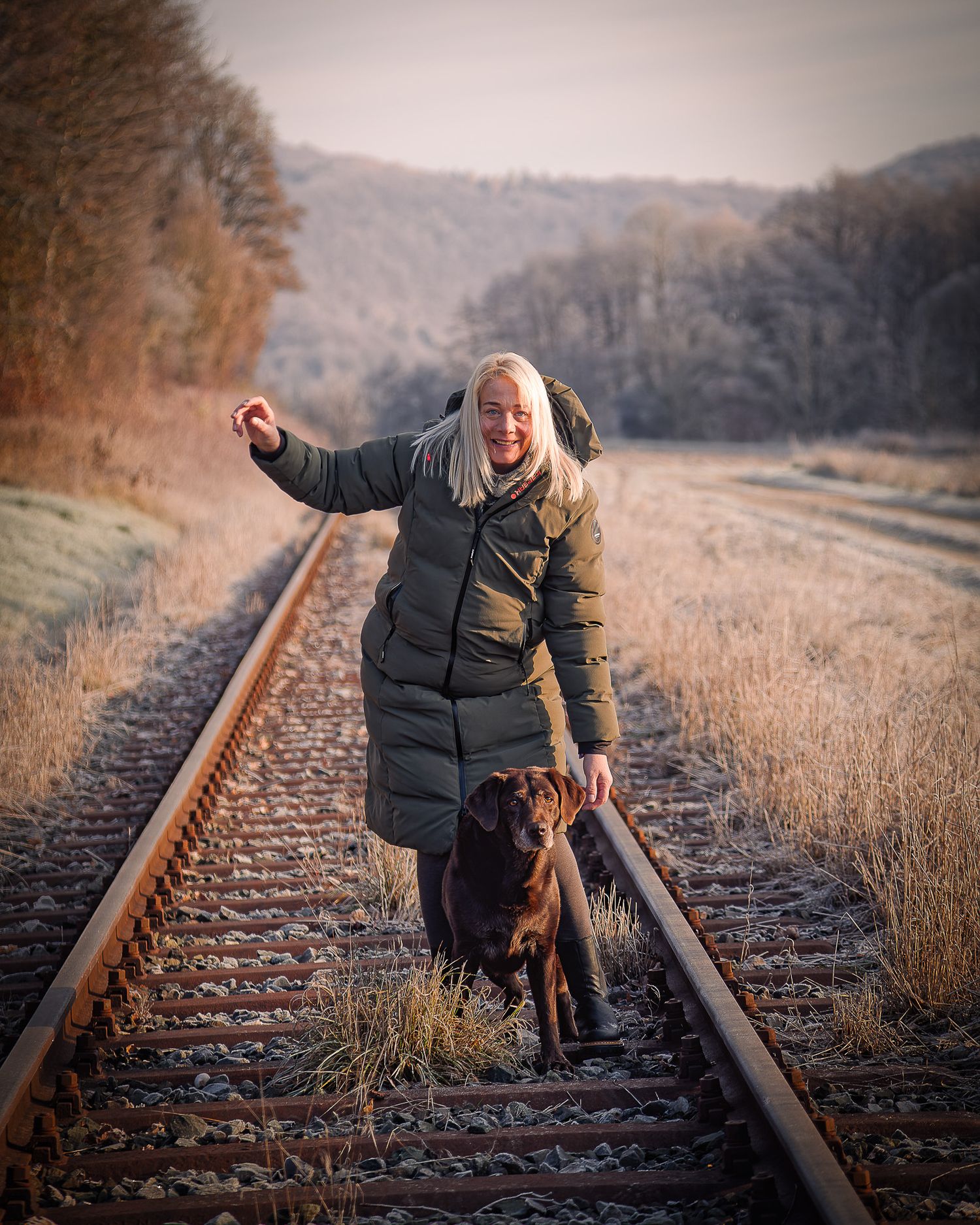 Eine Person im Wintermantel geht an einem frostigen Herbstmorgen mit einem  Hund entlang der Bahngleise in Gasseldorf Richtung Ebermannstad.