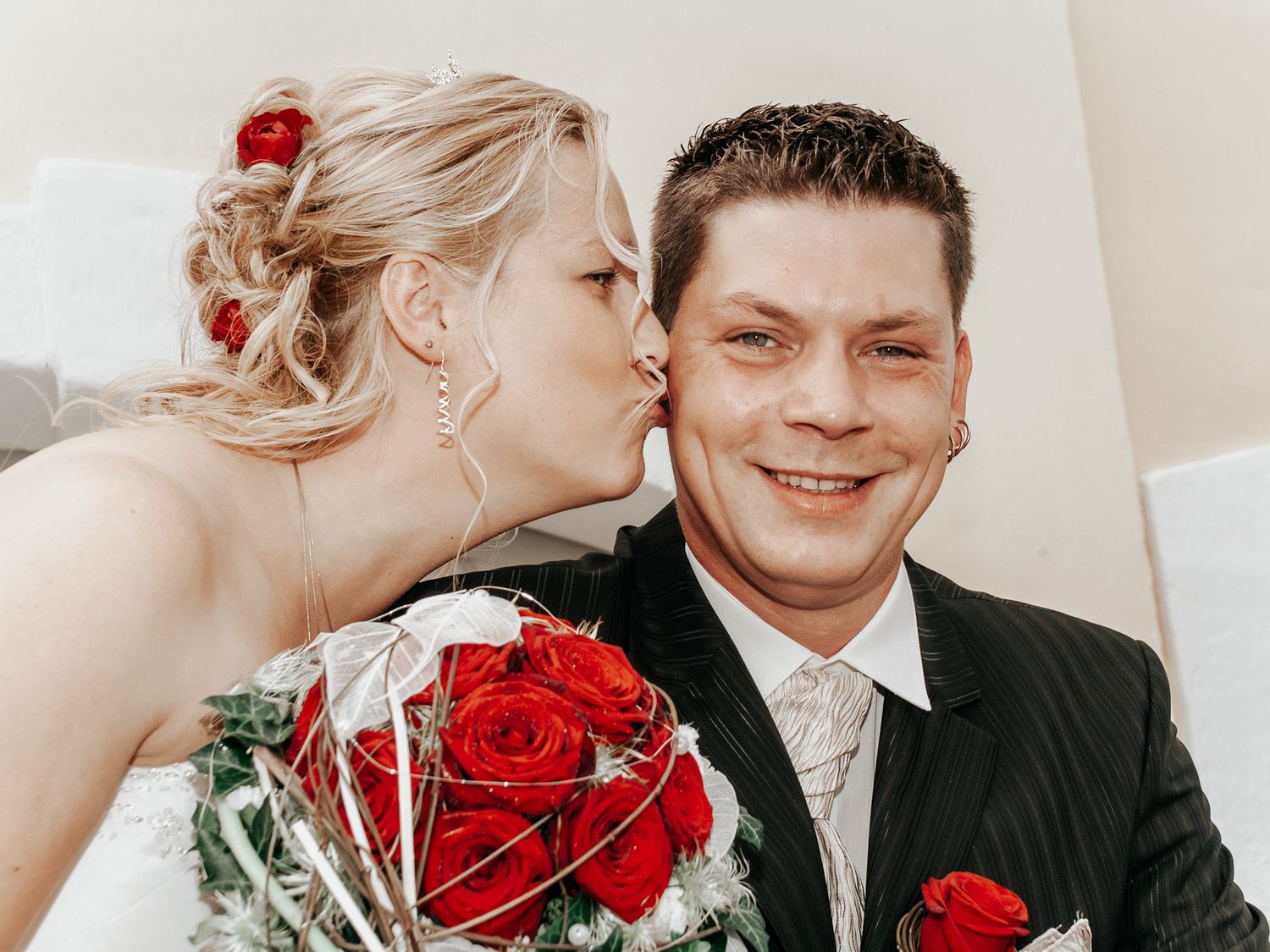 A couple shares romantic moments in a photo collage featuring bright red roses and formal attire.