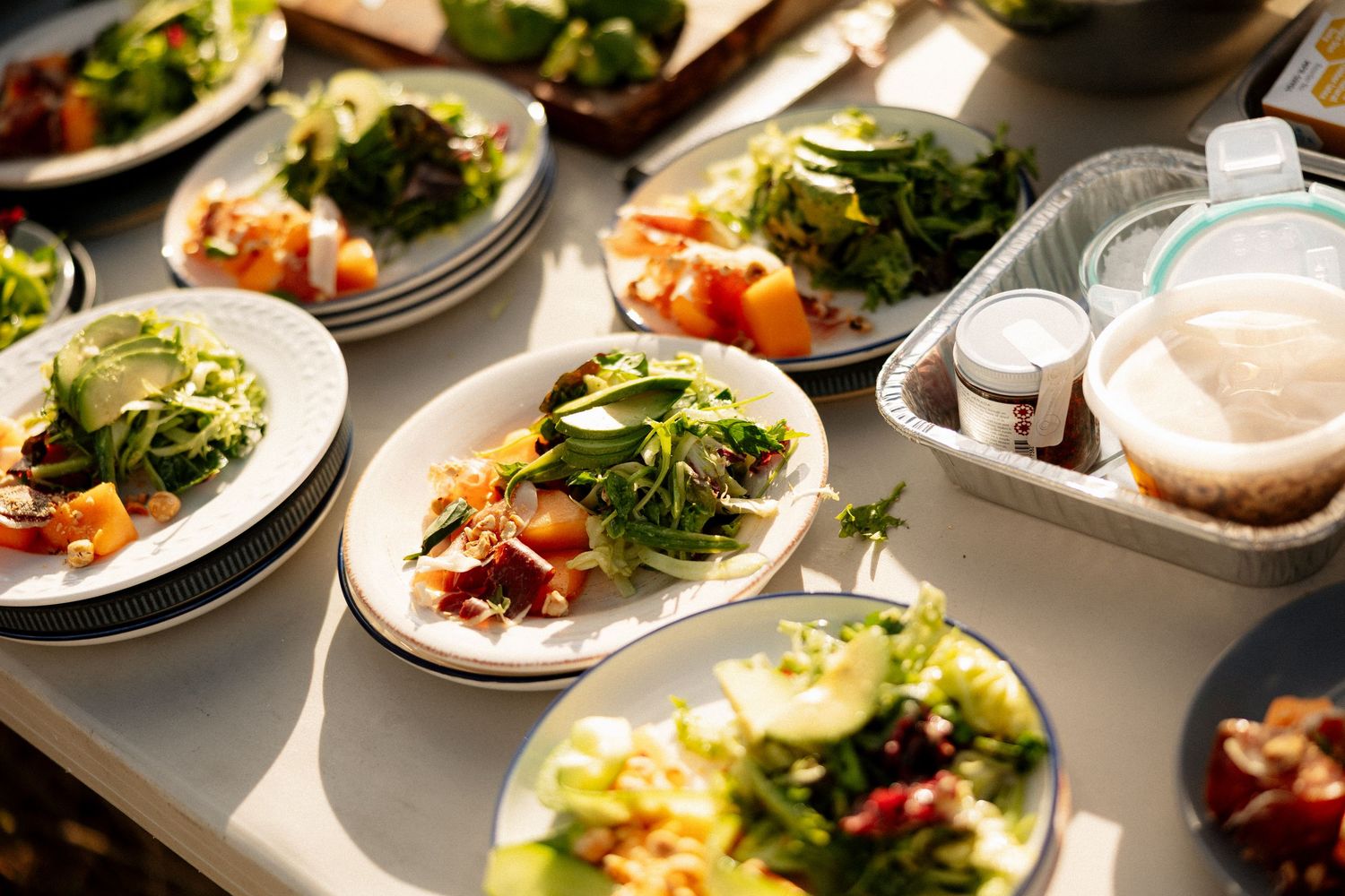 Assorted fresh salad plates with greens, vegetables, and colorful toppings displayed on a bright white surface.
