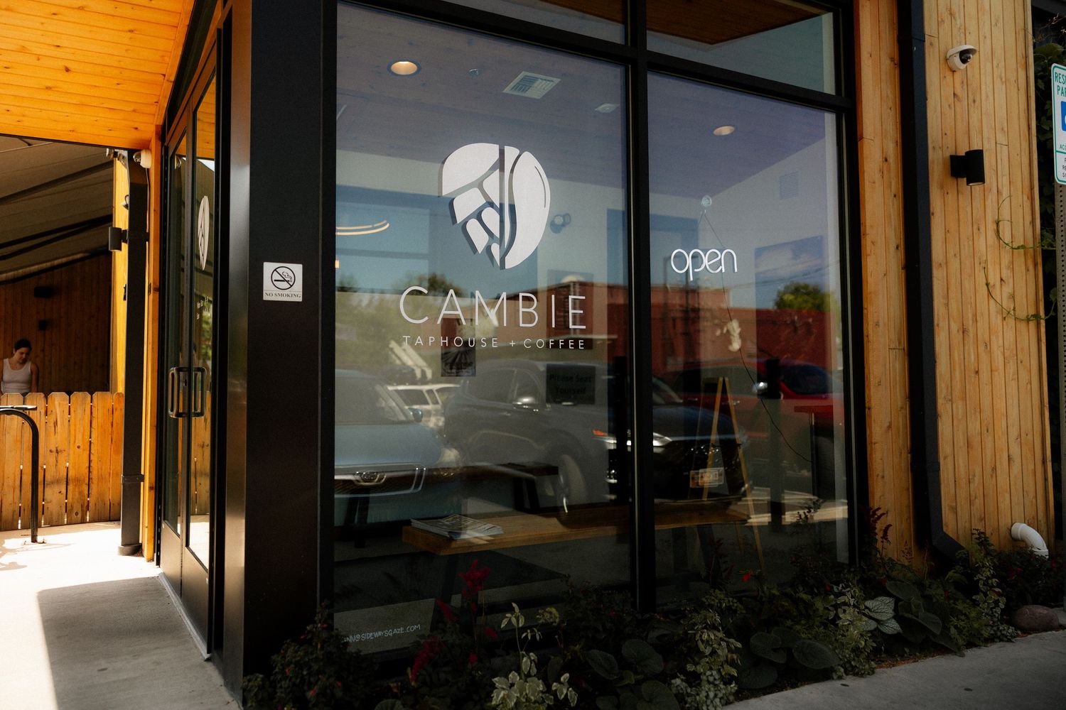 Exterior view of Cambie coffee shop with modern glass door entrance and wood panel siding.