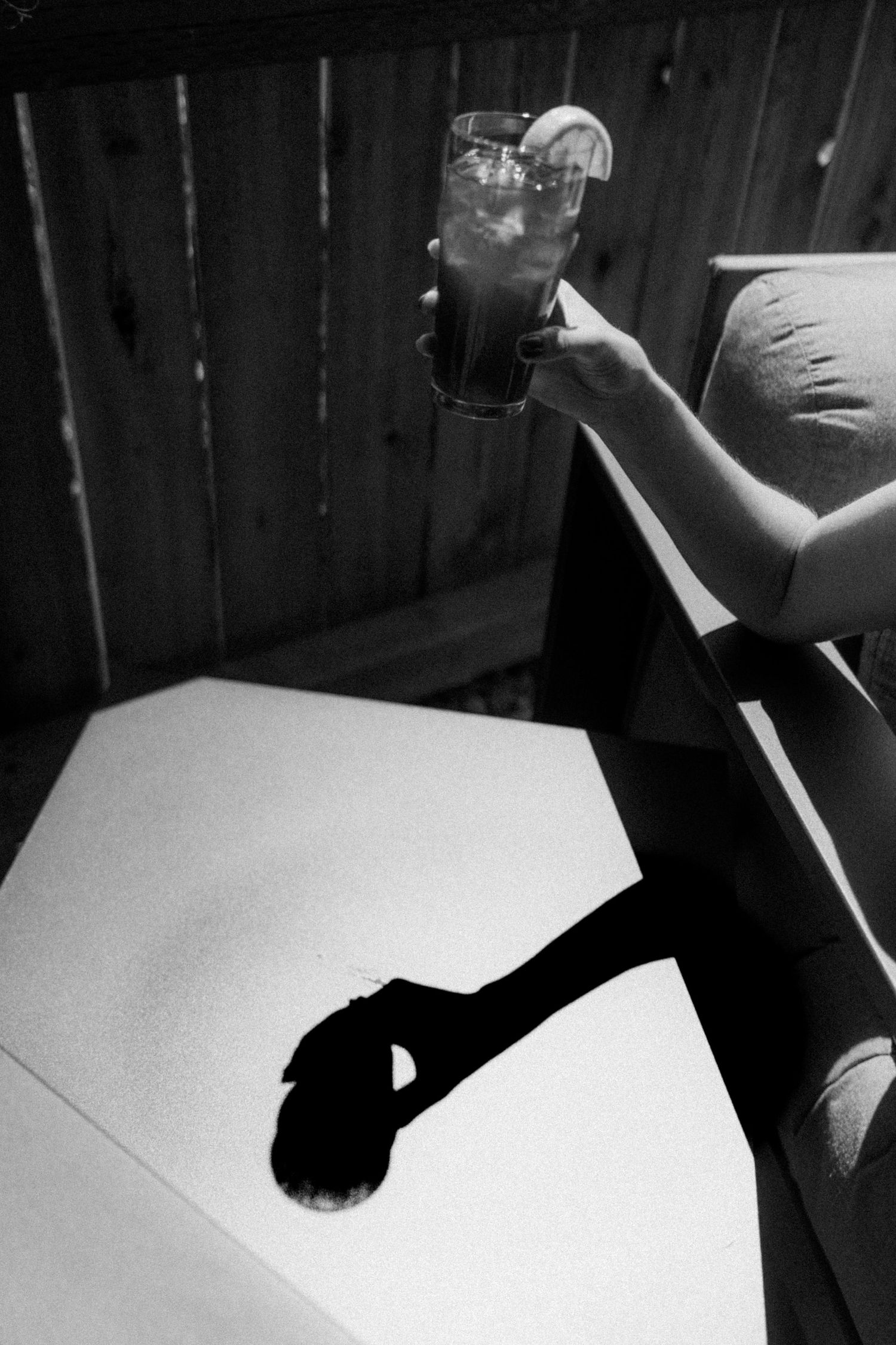 Black and white photo of a person holding a tall iced drink casting a dramatic shadow.