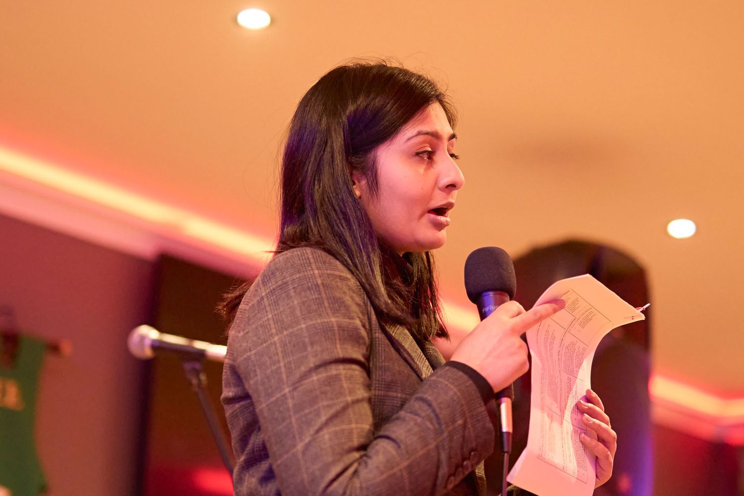 A series of photos shows someone speaking at what appears to be a business conference or meeting with pink lighting.