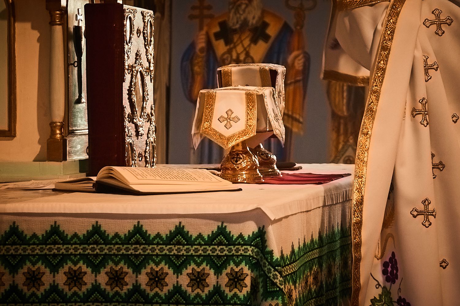Close-up of Orthodox altar with decorated cloth, religious book and ceremonial items.