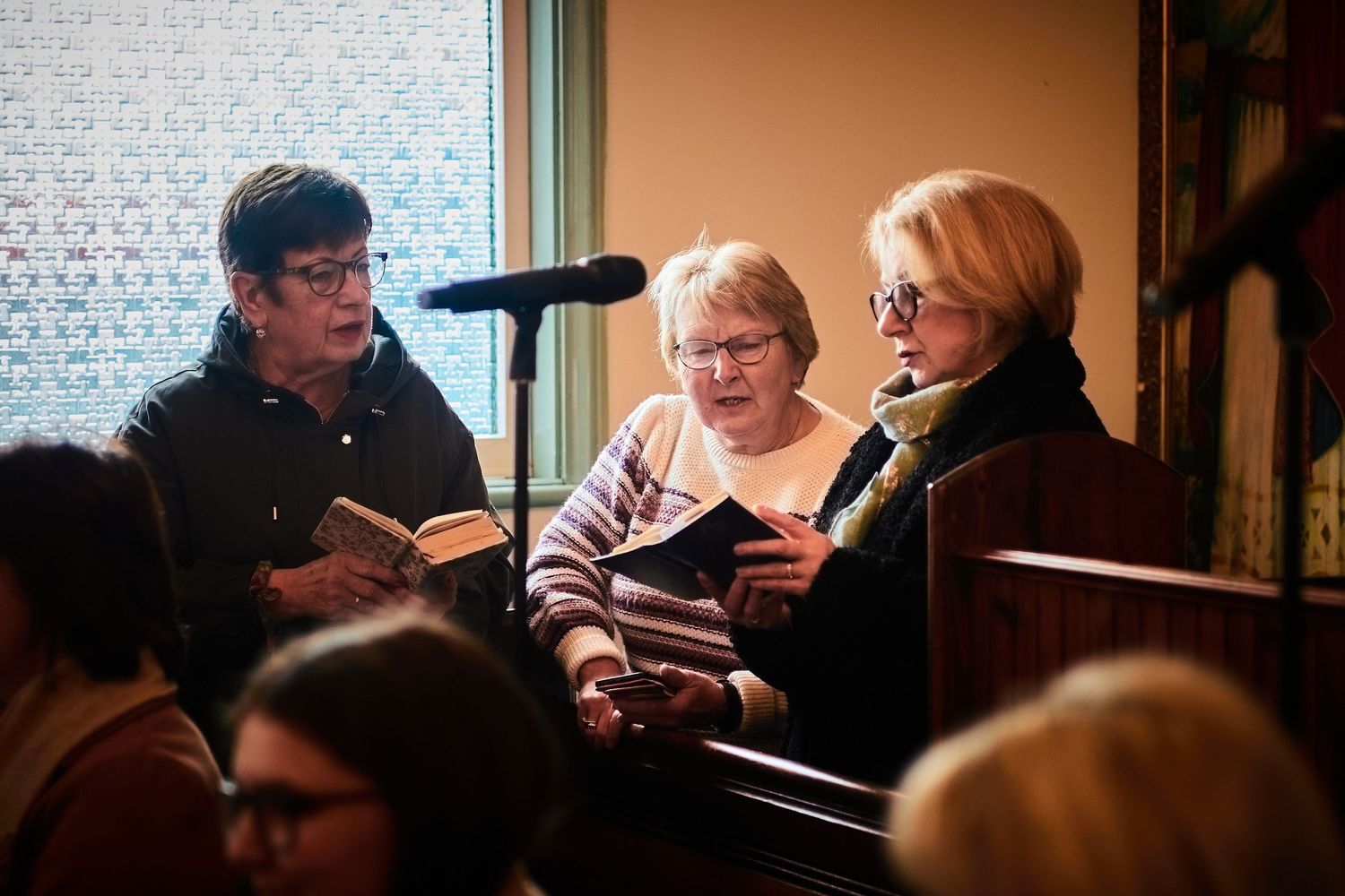 Group of people singing from hymnals during a church service.