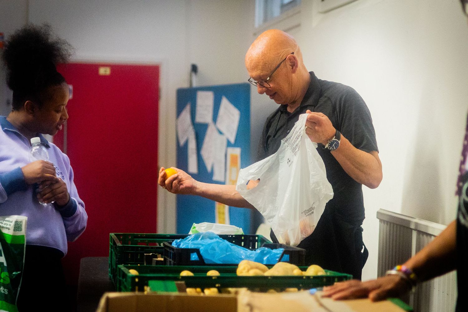 Volunteers working together at tables during a community food bank assembly line.