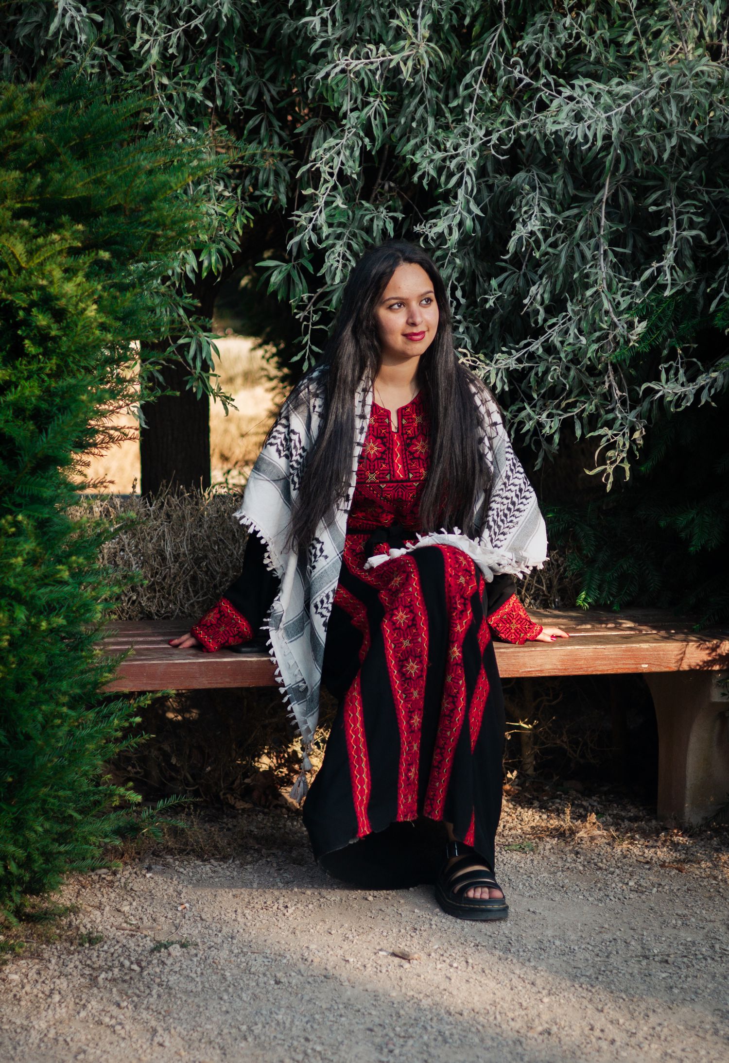 Artistic portrait featuring red dress and patterned shawl against willow tree branches.