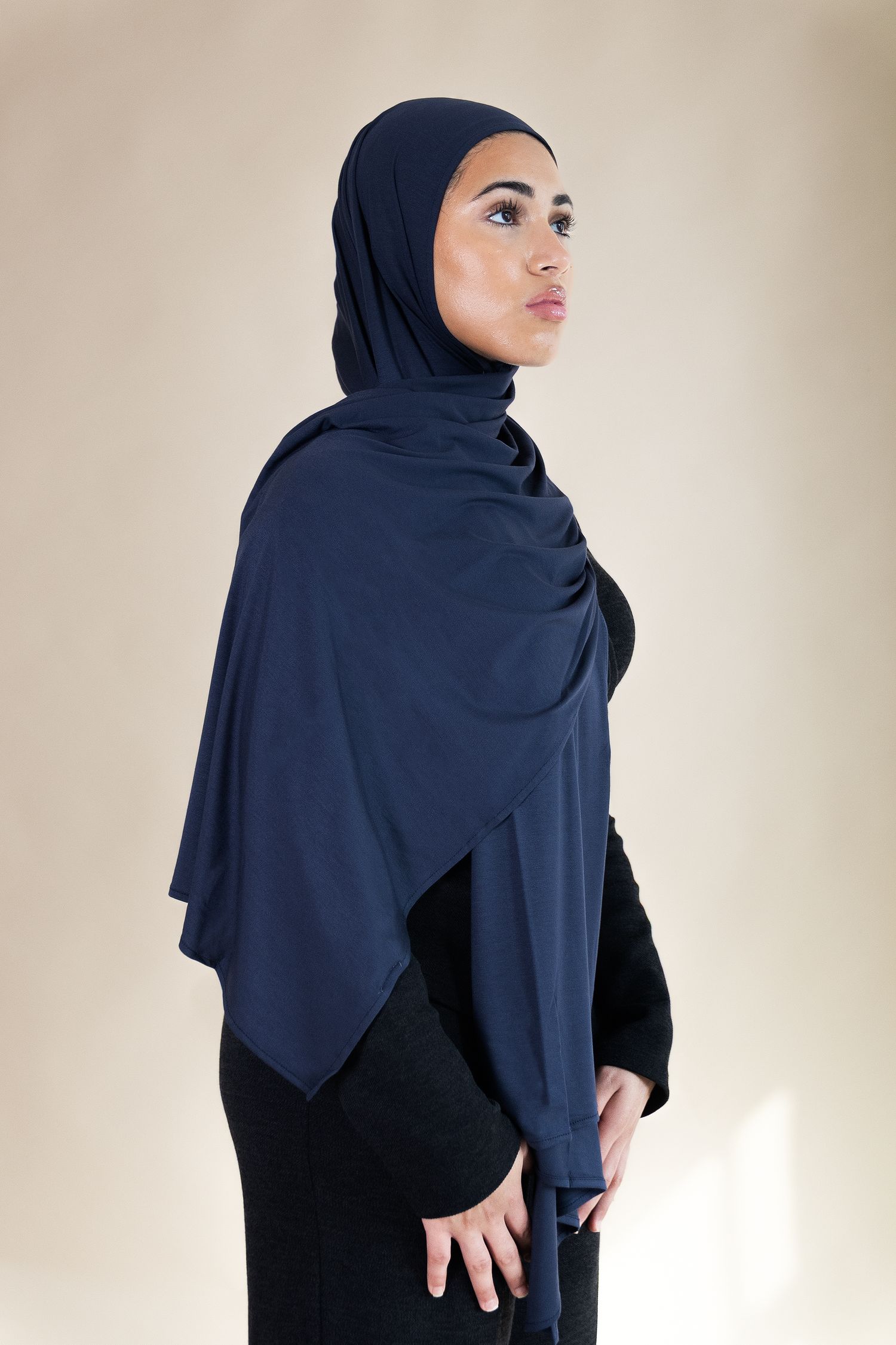 A series of photos showing a navy blue hijab styled in different poses against a light neutral background.
