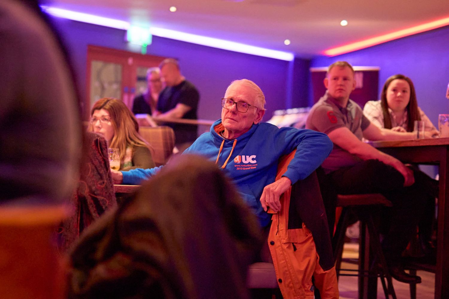 People seated in a dimly lit restaurant with purple ambient lighting and modern decor.