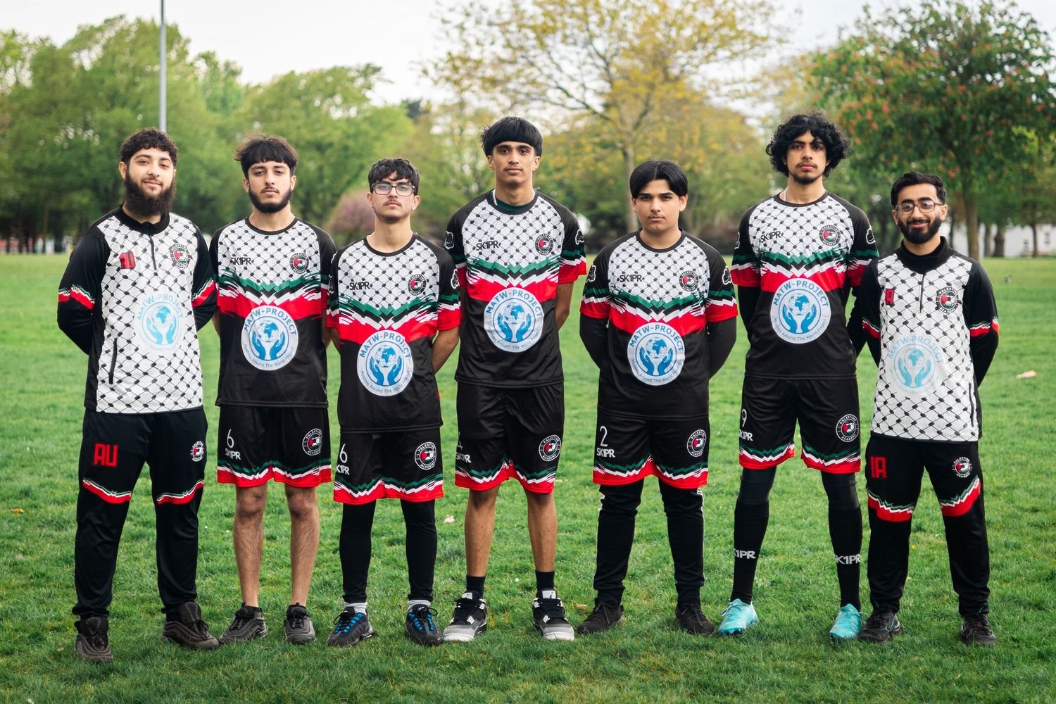 Soccer team members line up wearing coordinated white and black uniforms with geometric patterns.