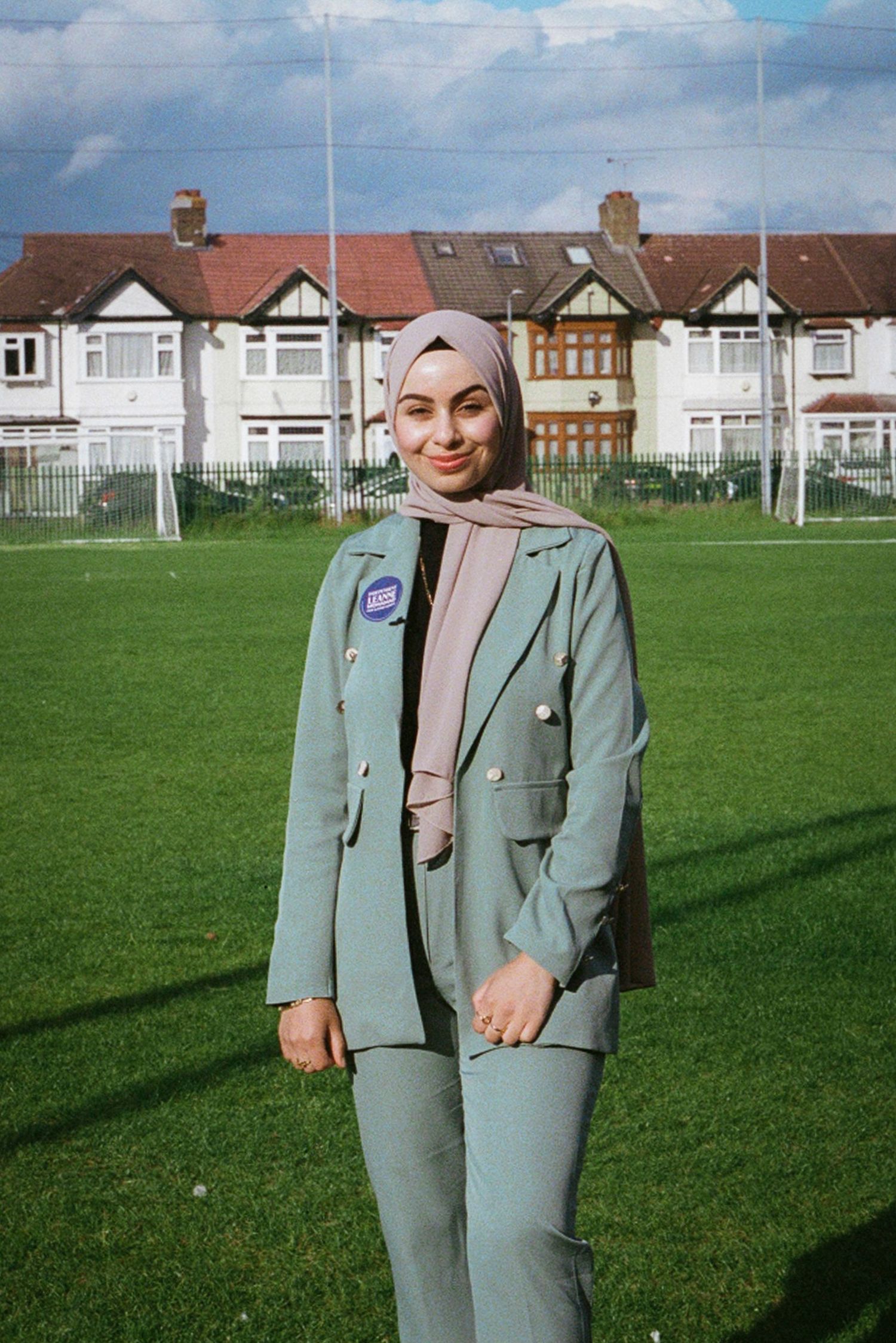 Professional fashion photography of a mint green suit ensemble on a sunny field.