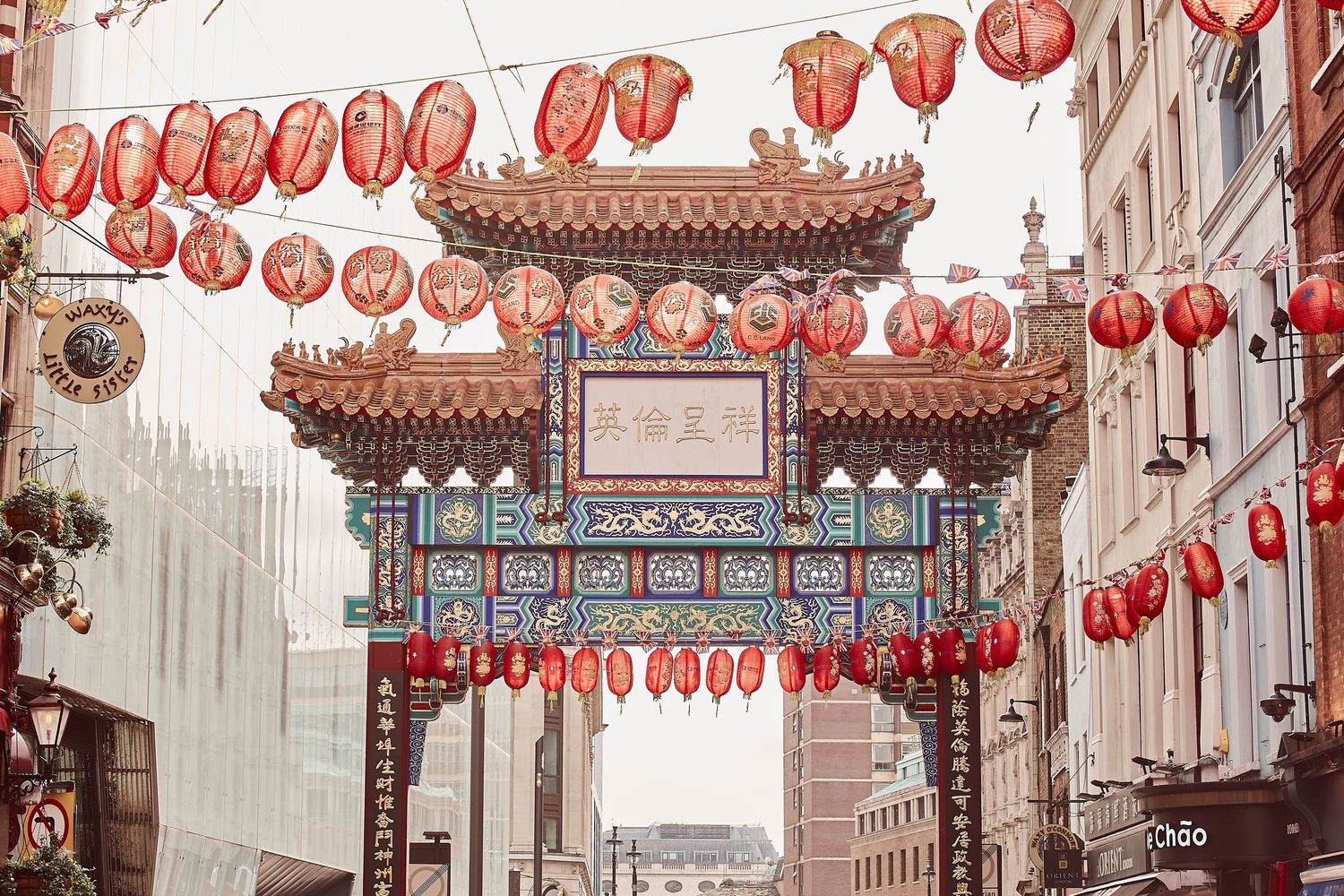 Traditional Chinese gateway arch with red lanterns in urban setting.