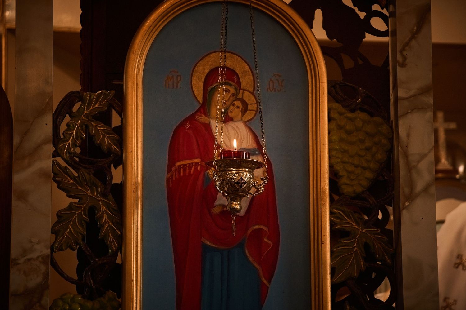 Religious icon of Virgin Mary and Child Jesus illuminated in ornate gold frame.