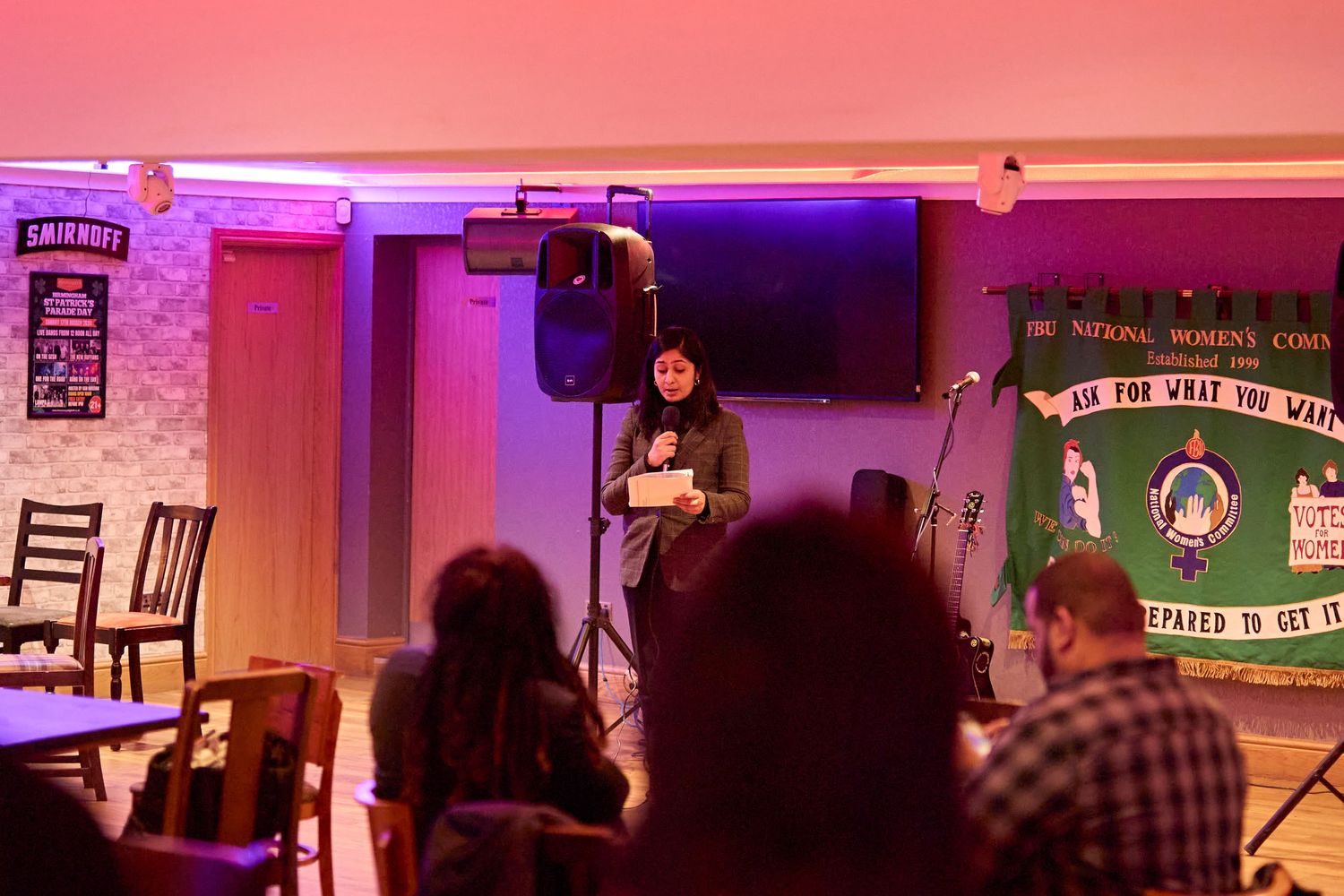 Blurry red and pink lights illuminate a dimly lit interior performance space.