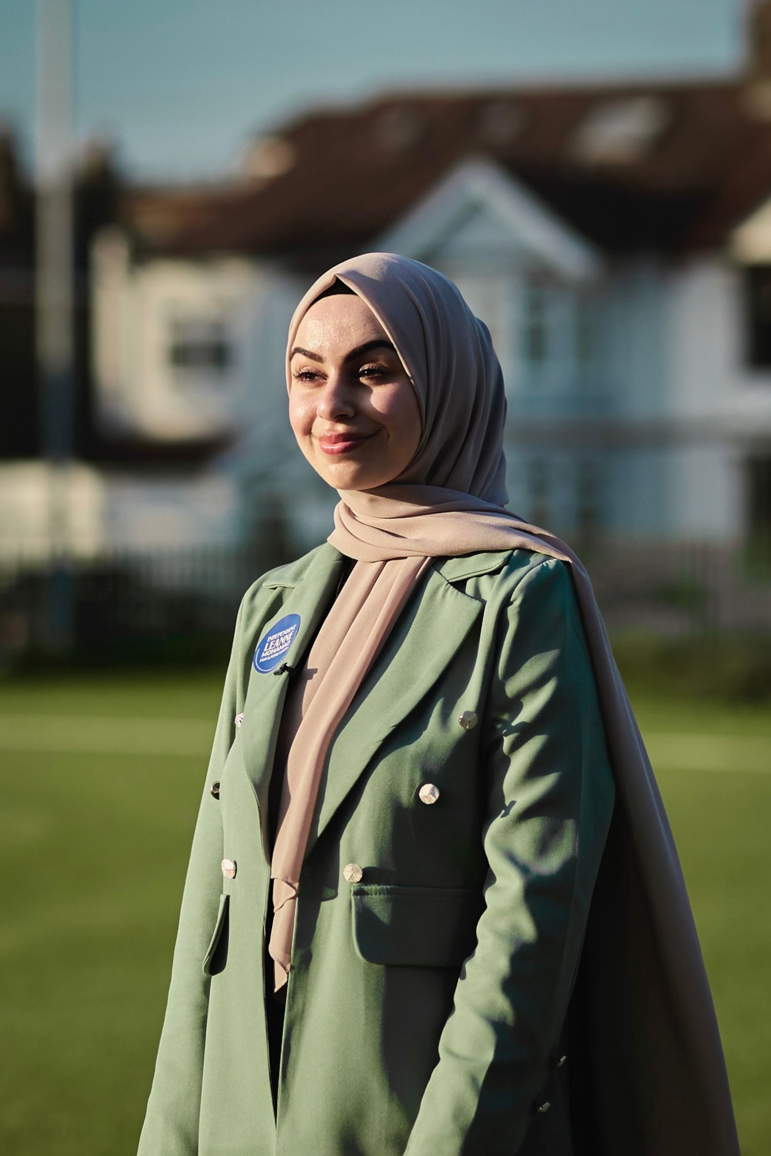 A mint green blazer outfit with beige hijab captured in an outdoor setting during golden hour.