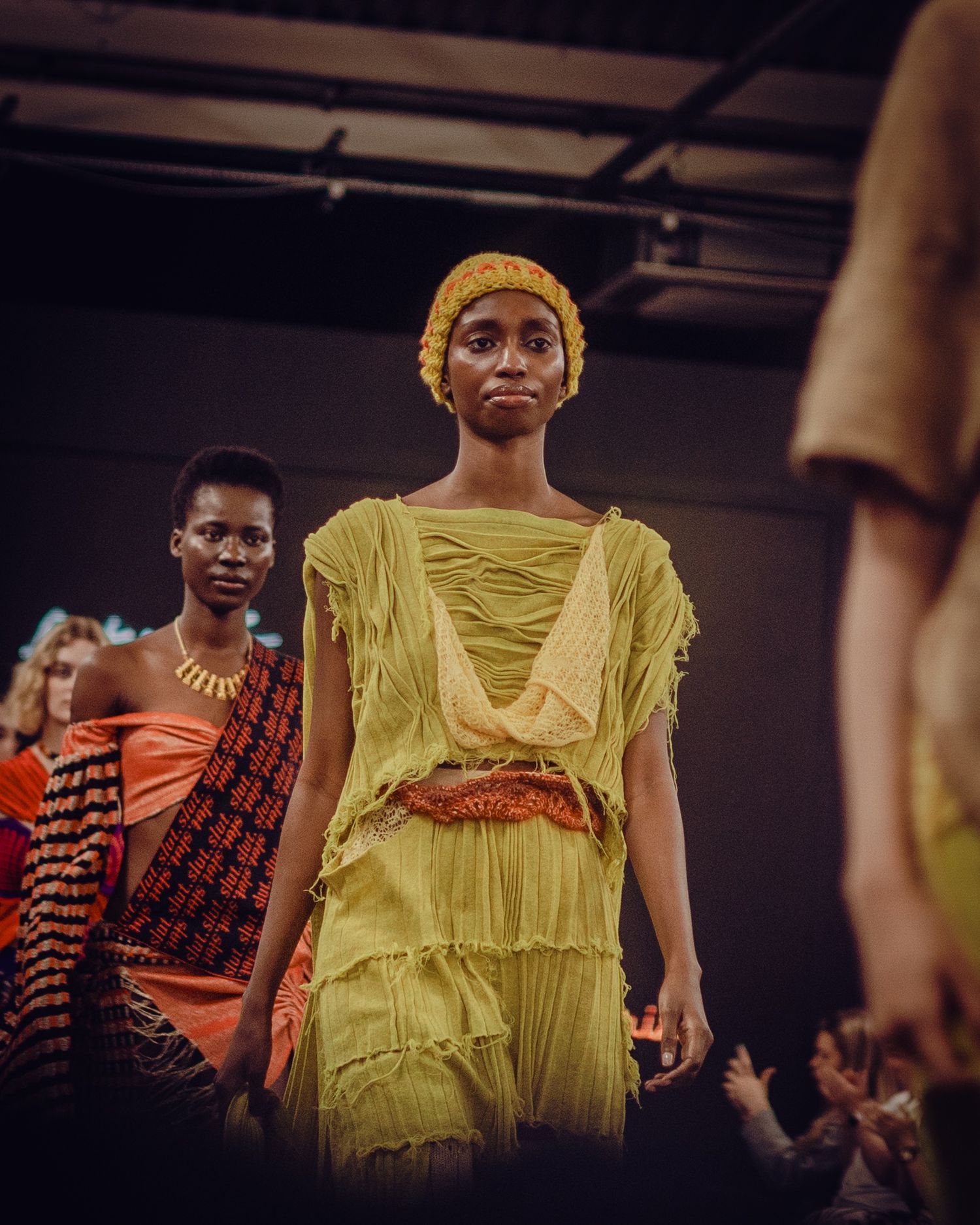 Yellow draped dress with layered details presented at fashion show.