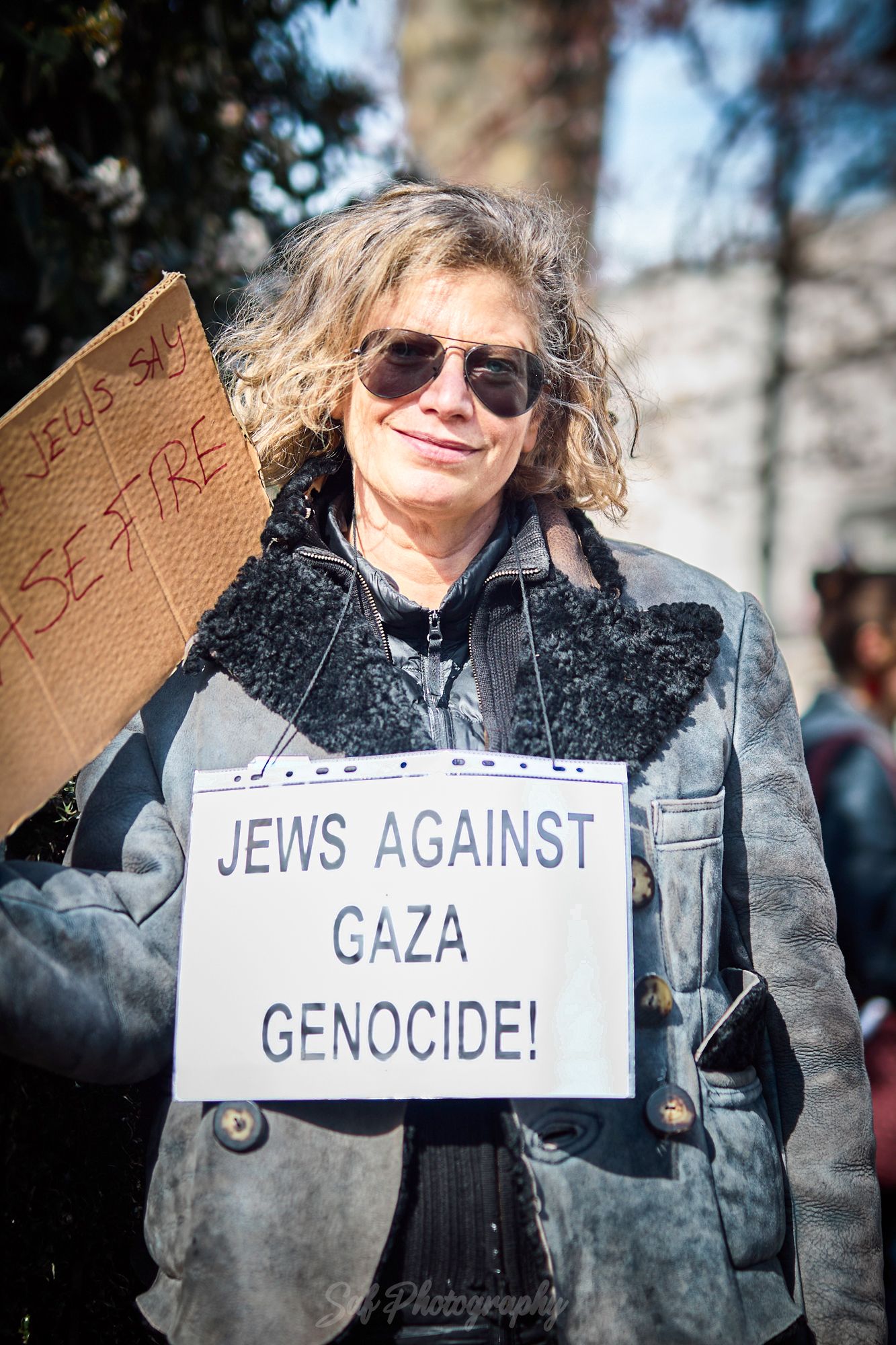 Person holding a Jews Against Gaza Genocide sign at a protest rally outdoors.