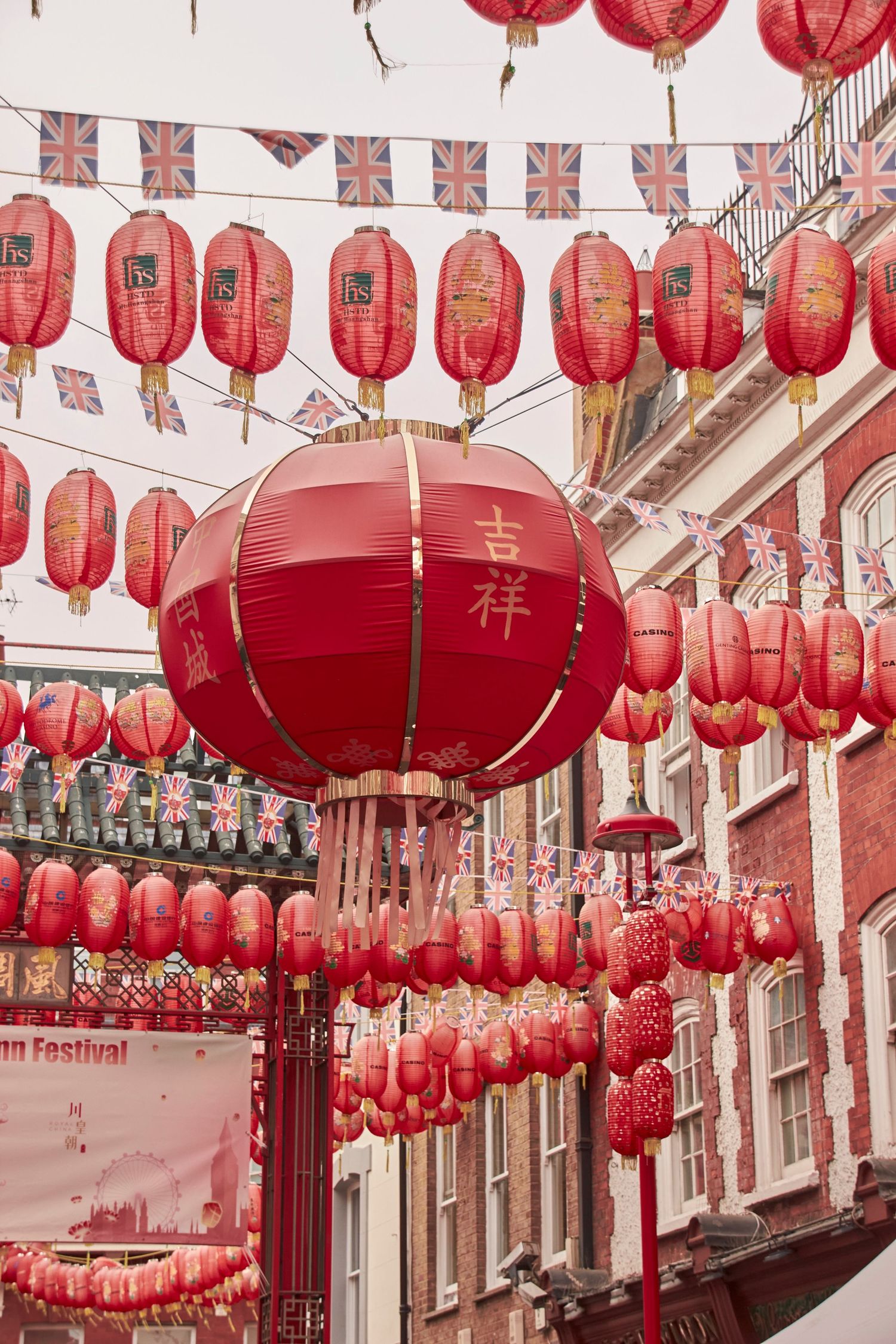 Red Chinese lanterns and British Union Jack flags hanging above a London Chinatown street.