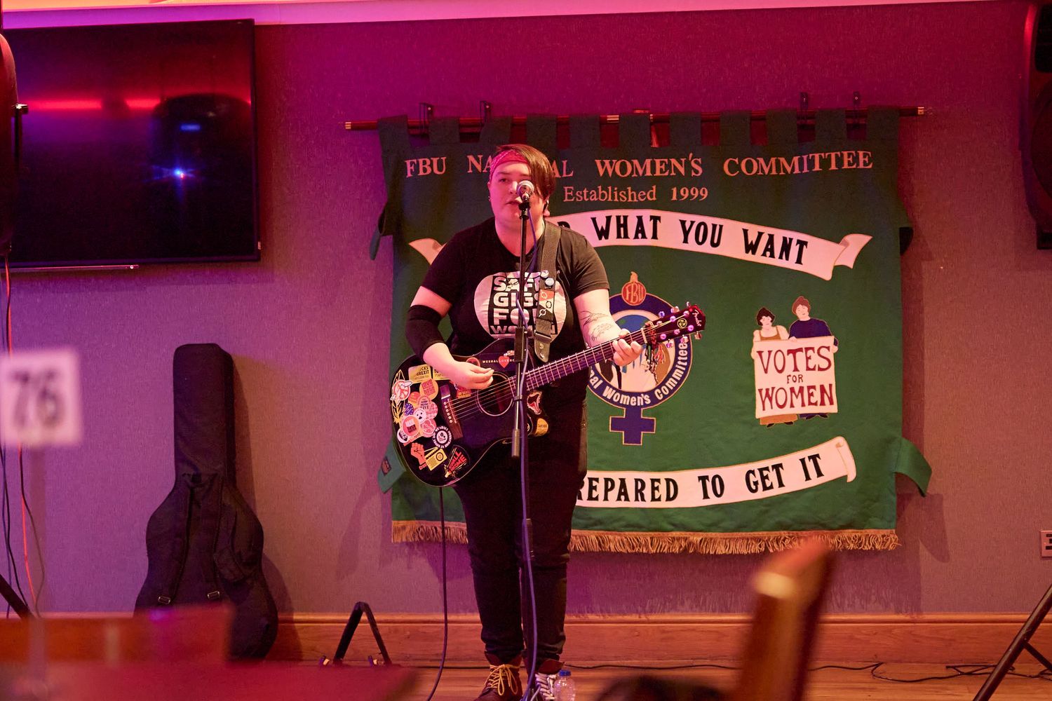 Stage performance with green banners and pink lighting during a live entertainment event.