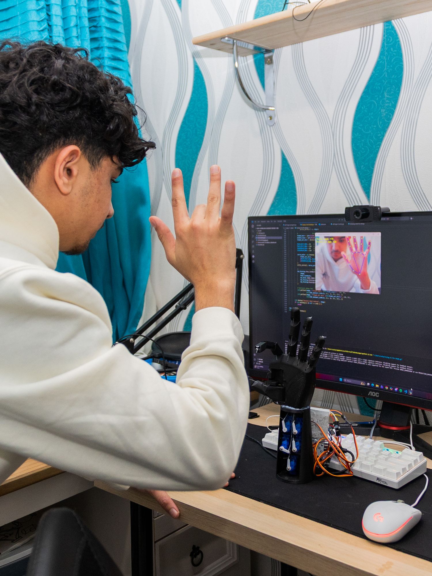 A person in a white hoodie works at a desk setup with multiple computer monitors displaying digital content.