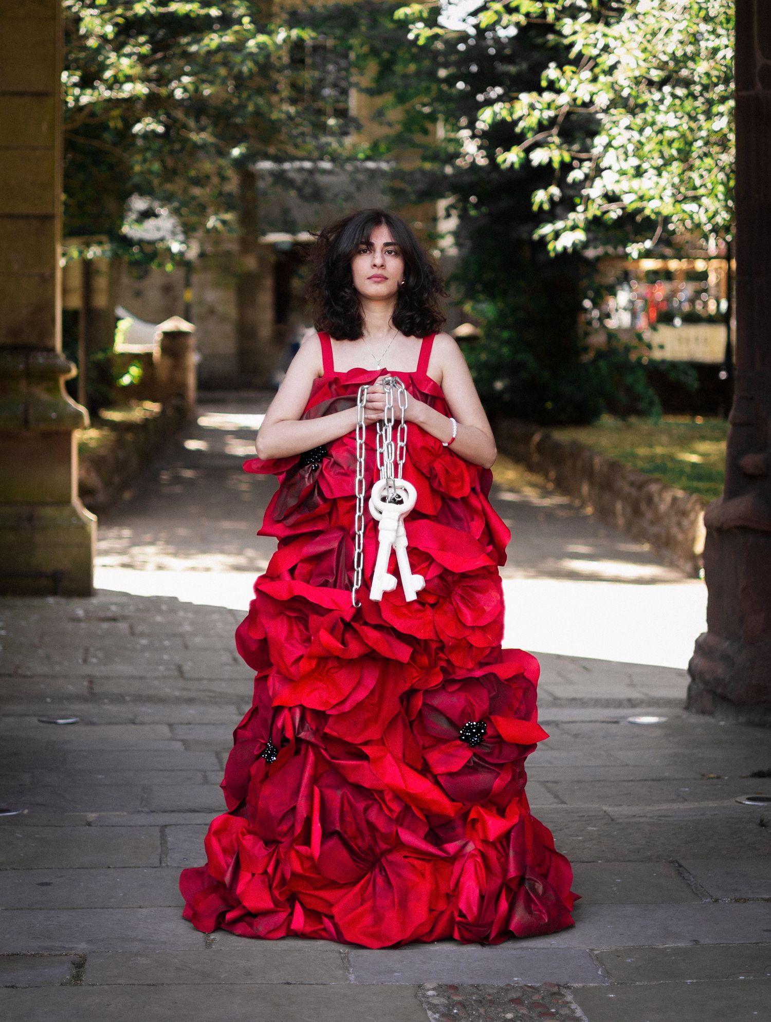 A vivid red ruffled gown with white rope accessory photographed at a historic stone location.