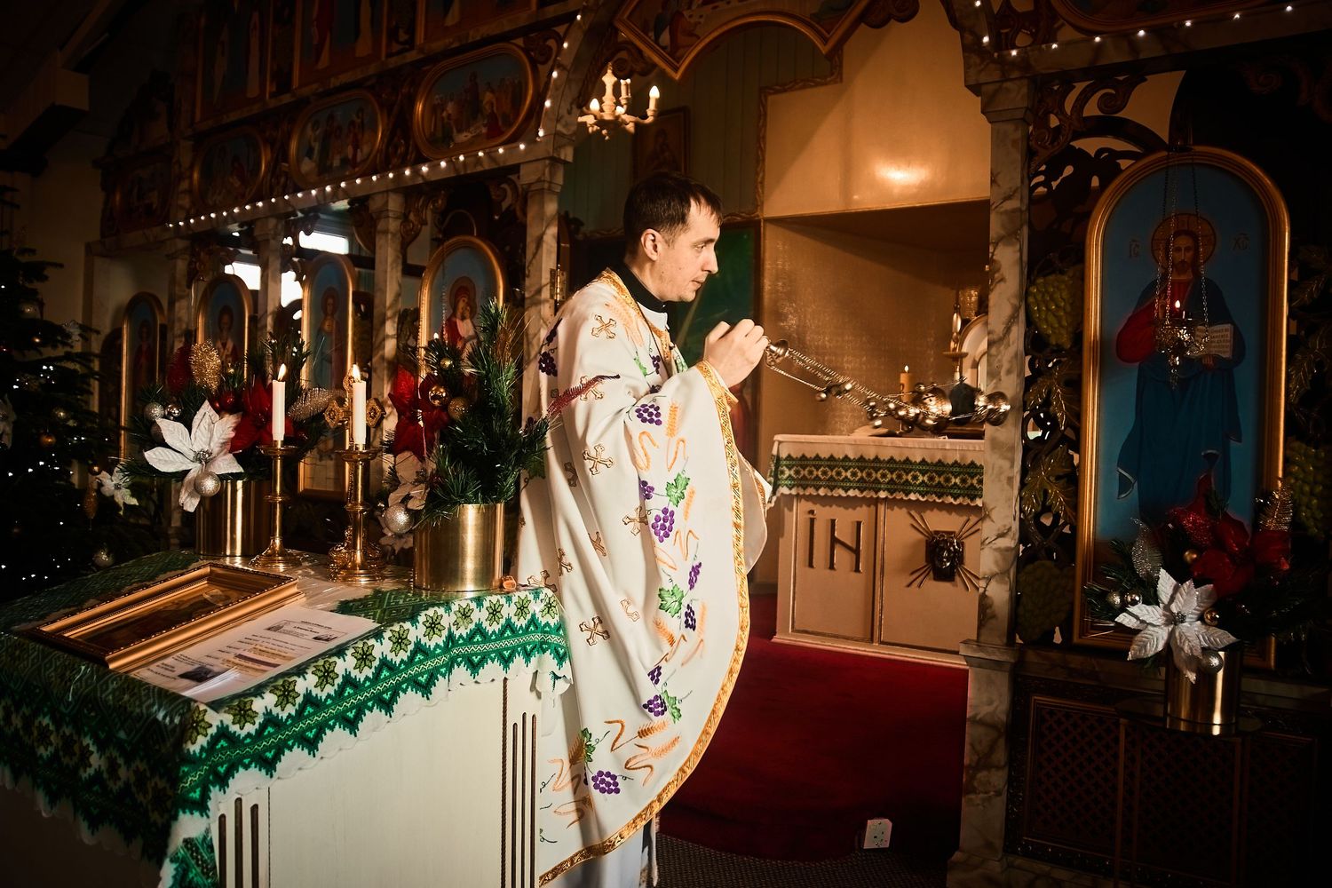 Traditional Orthodox church decorated with hanging lights, icons, and holiday greenery.