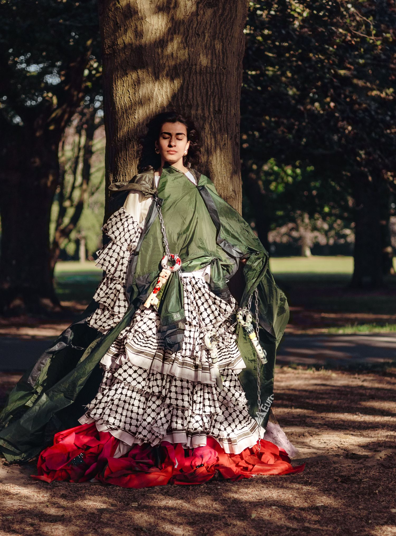 Dramatic fashion photo showing a flowing dress with olive green top, black and white polka dots, and red ruffled hem in a forest setting.
