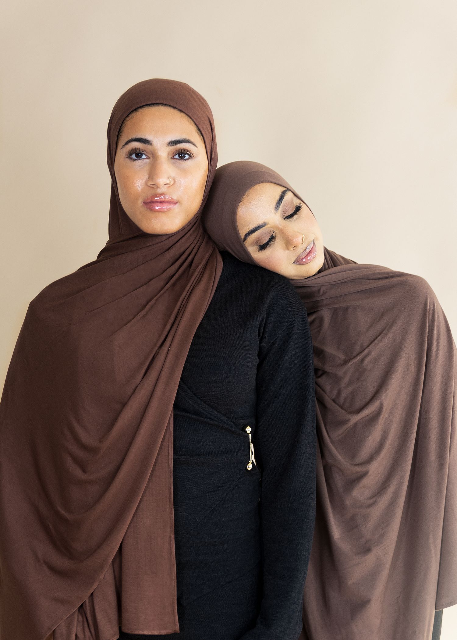 Two women in brown and black hijabs pose together in a series of affectionate side-by-side portraits.