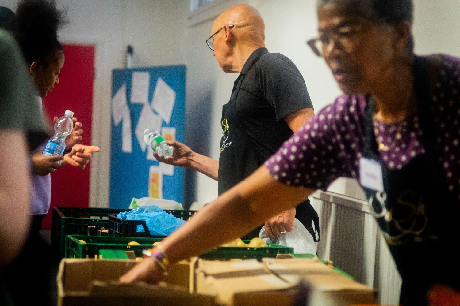 Volunteers assembling food packages at long tables during a community service event.