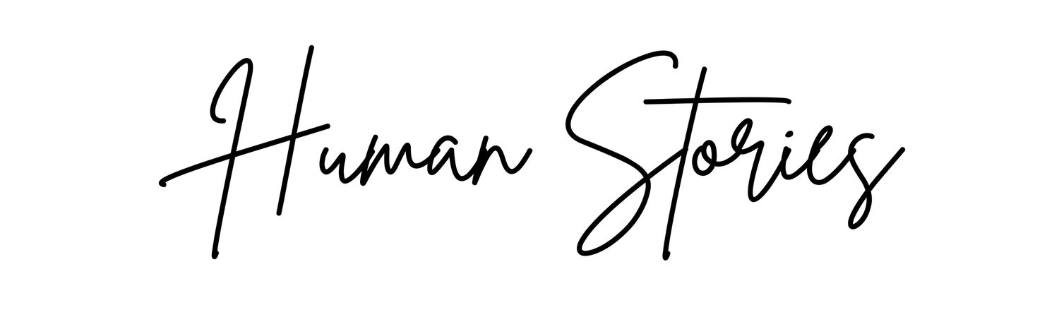 A handwritten text in black ink reads 'Human Stories' on a white paper background.