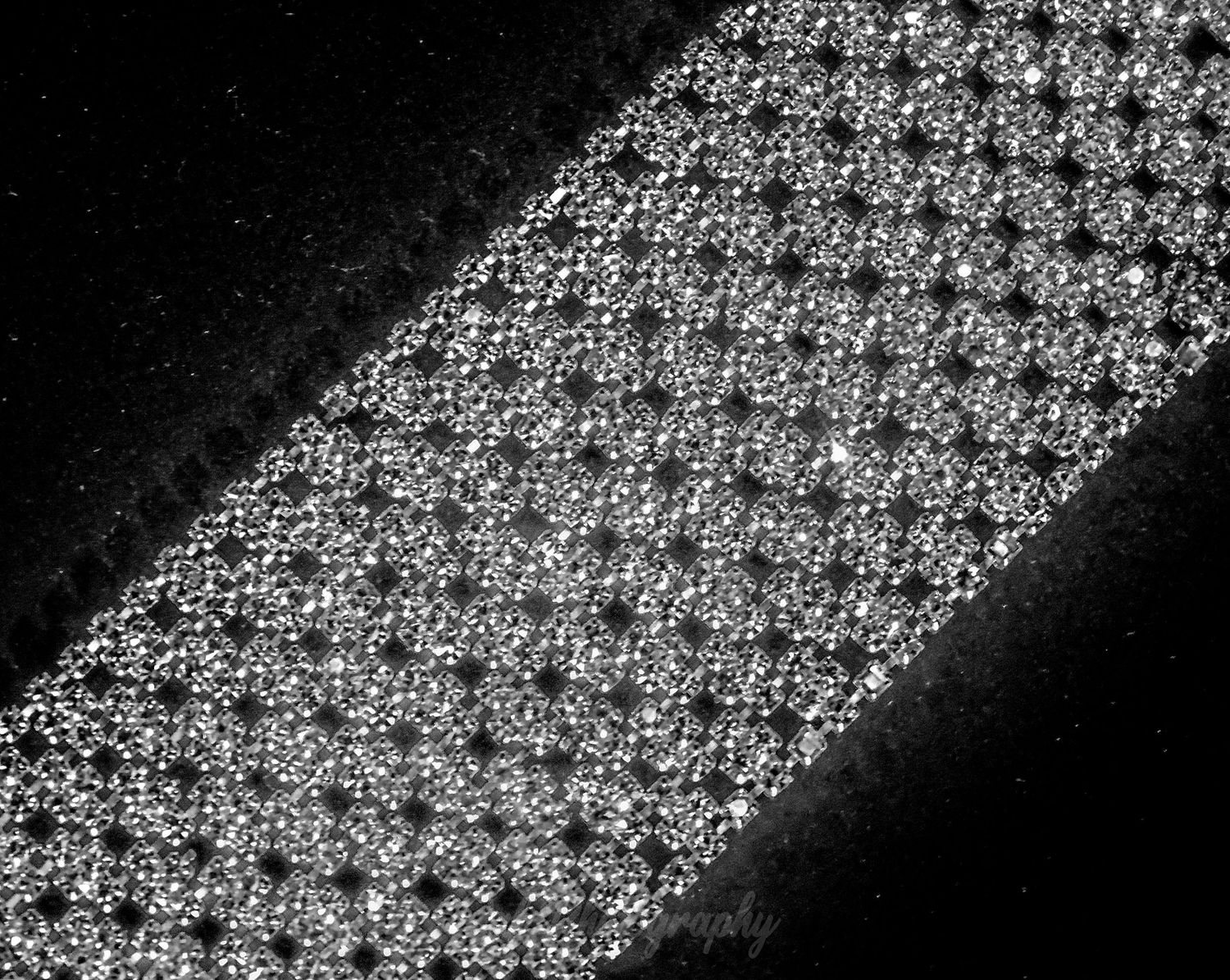 A diagonal strip of intricate black and white lace pattern showing fine detail and texture against a dark background.